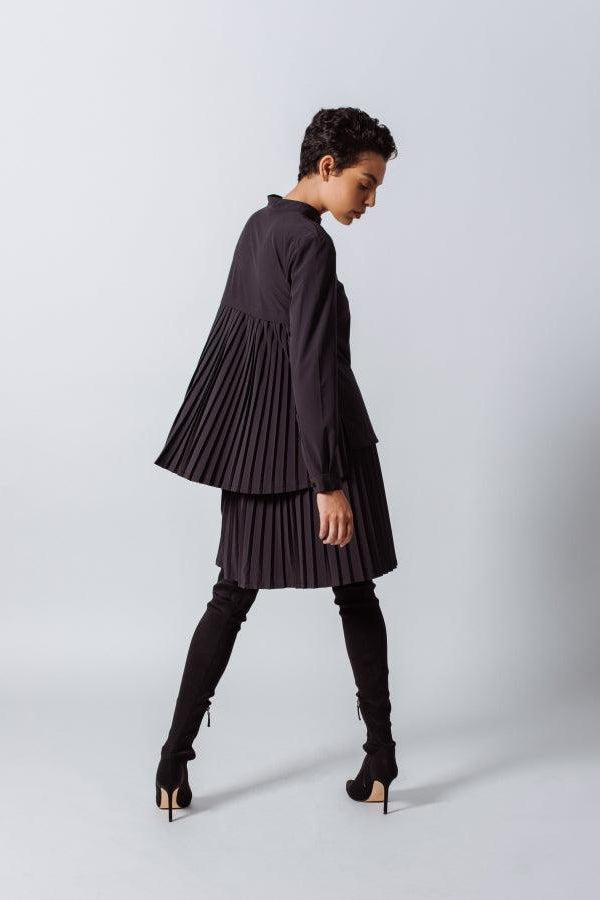 Woman wearing a black pleated dress on a white background