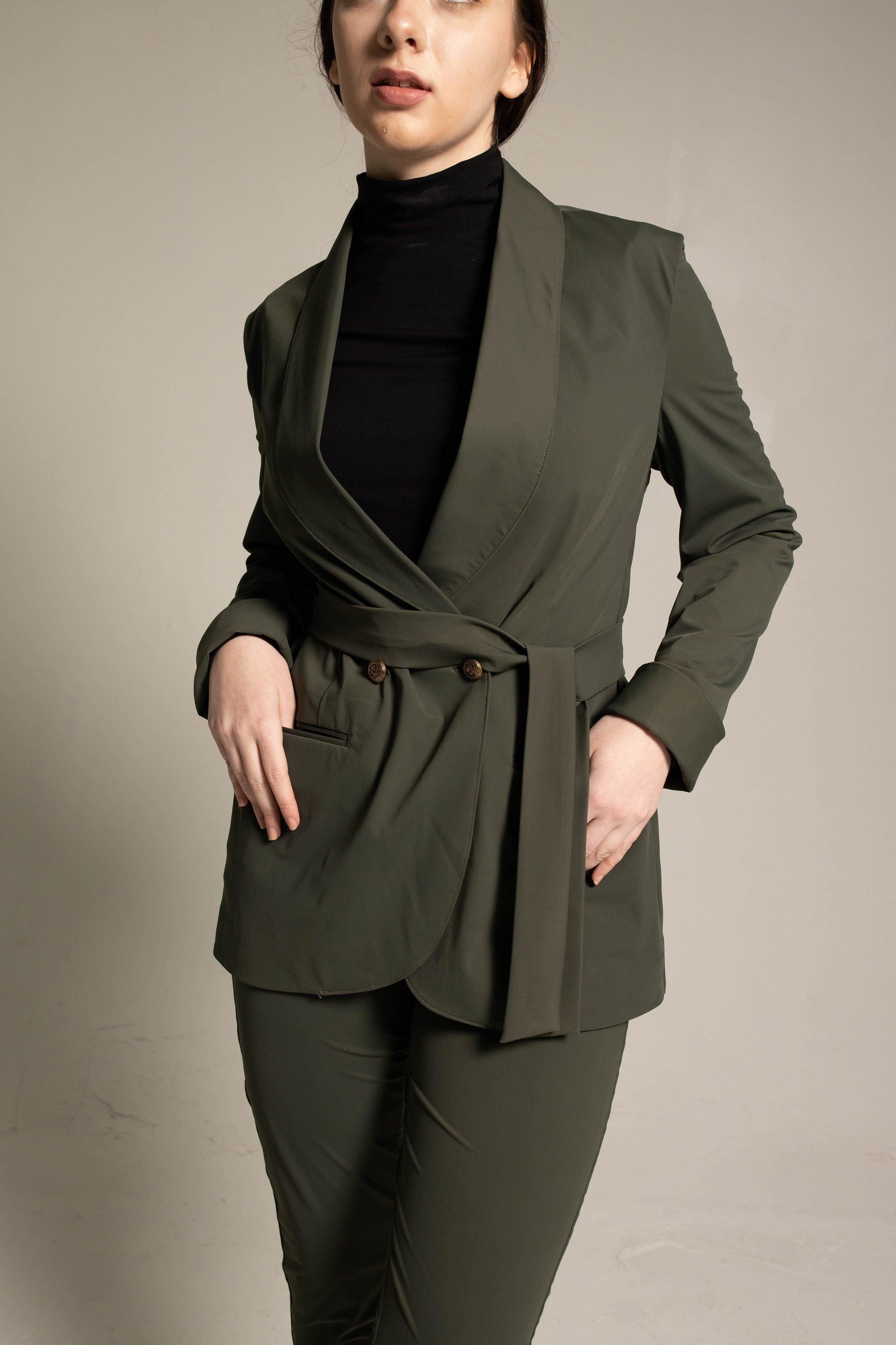 Woman wearing a green suit with a black turtleneck against a beige background