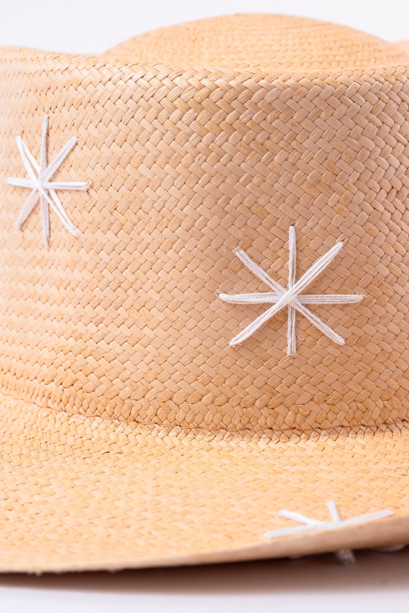Beige straw hat with white star patterns on a light background