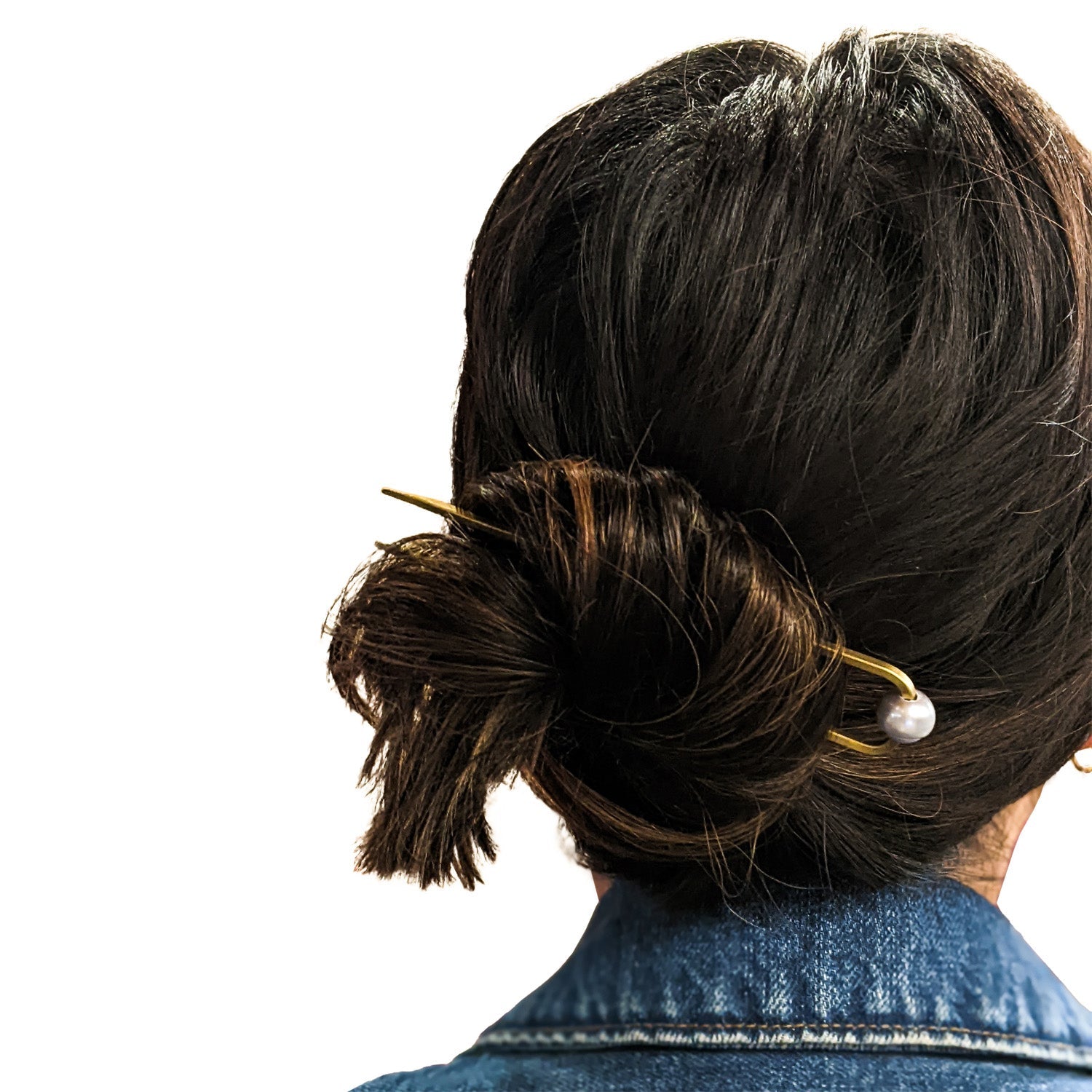 Back view of a person with a bun hairstyle wearing a denim jacket on a white background