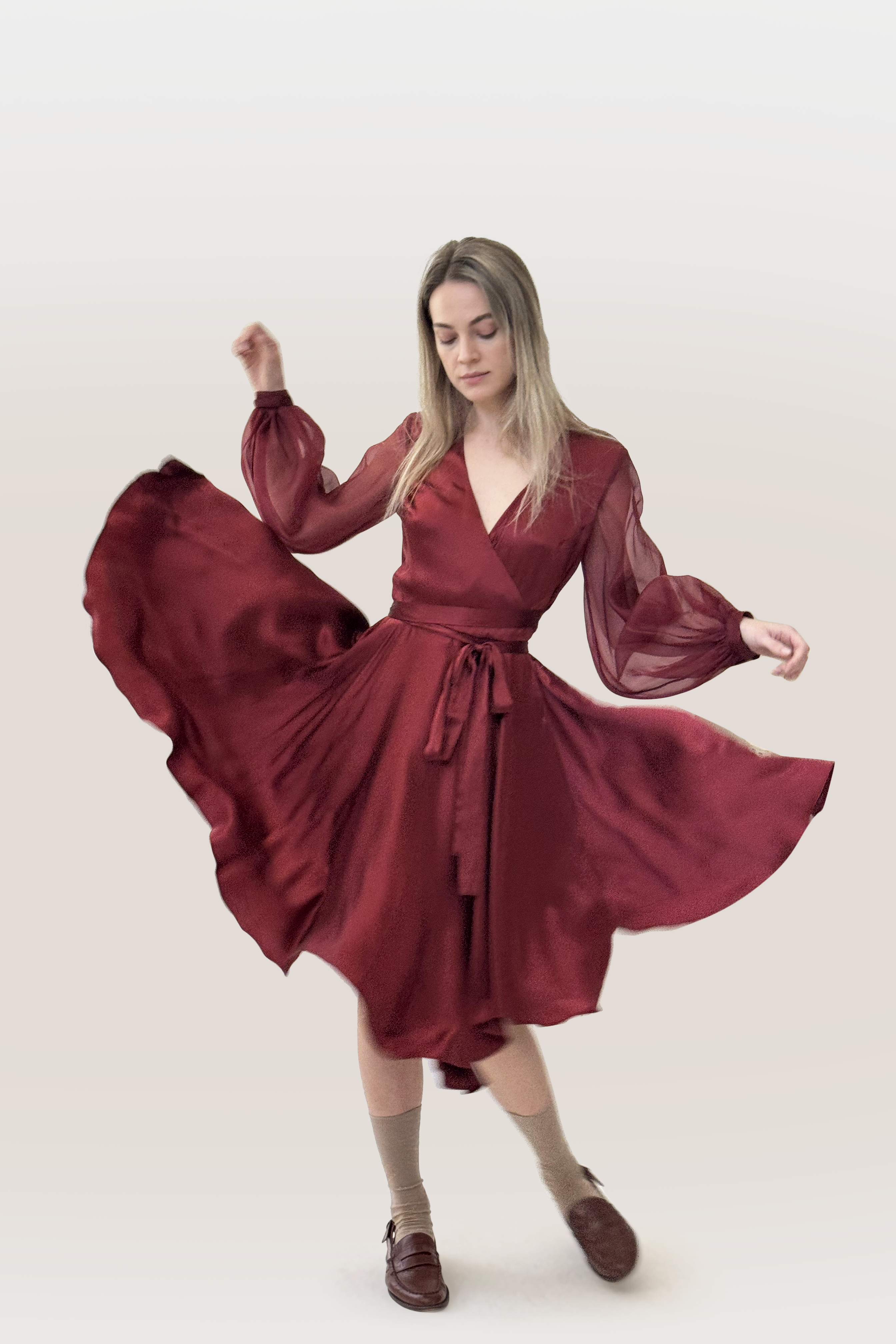 Woman wearing a red wrap dress with long puffy sheer sleeves on a white background