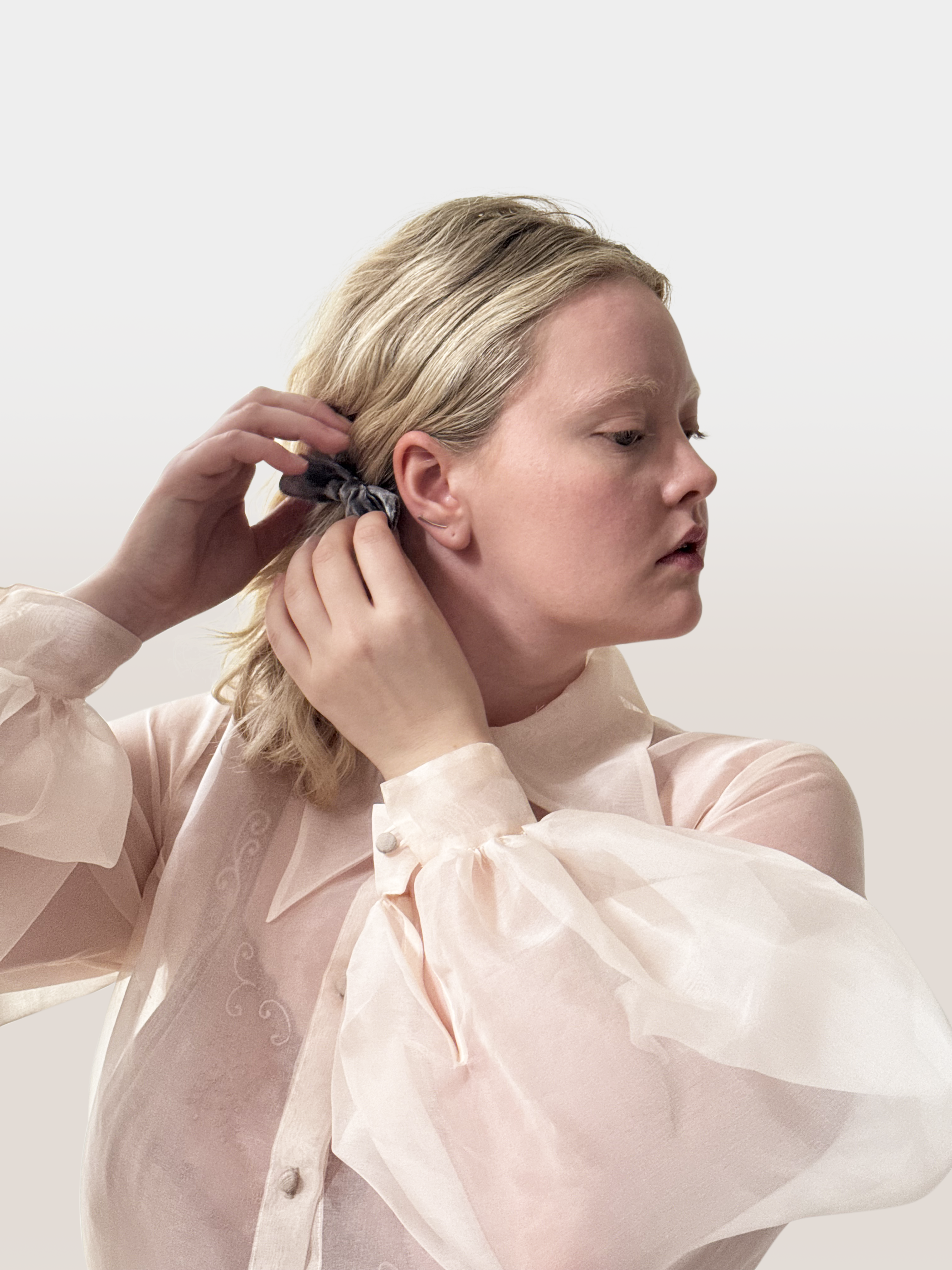 Woman adjusting her hair with a neutral background