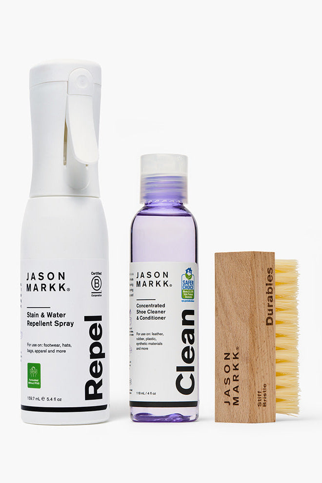 Set of Jason Markk shoe care products including a spray bottle, cleaner, brush, and wooden block on a white background.