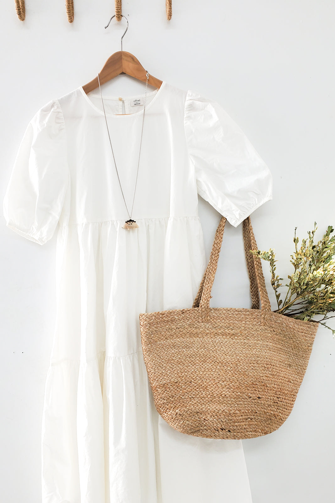 White dress with a straw bag on a white background