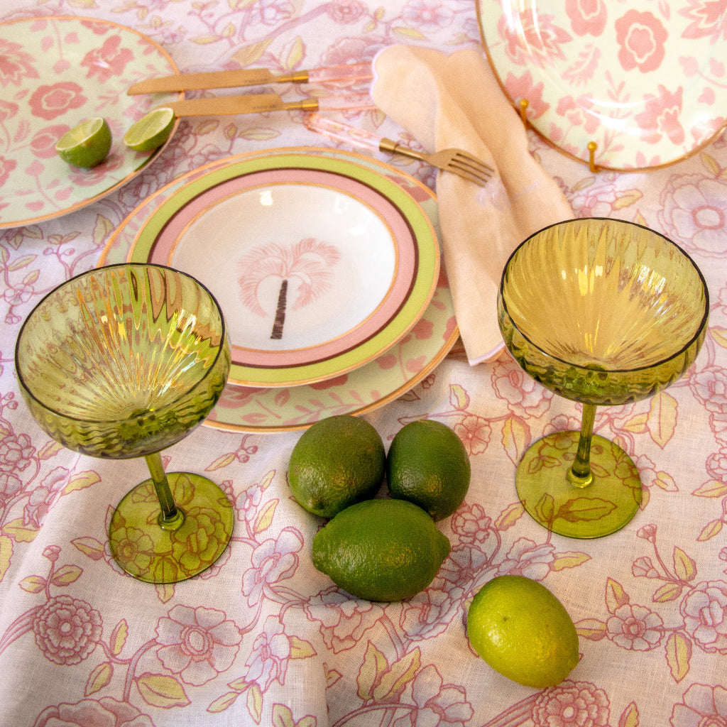 Green glass goblets and limes on a floral tablecloth