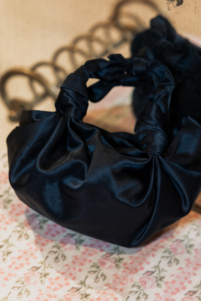 navy blue satin handbags on a floral fabric background