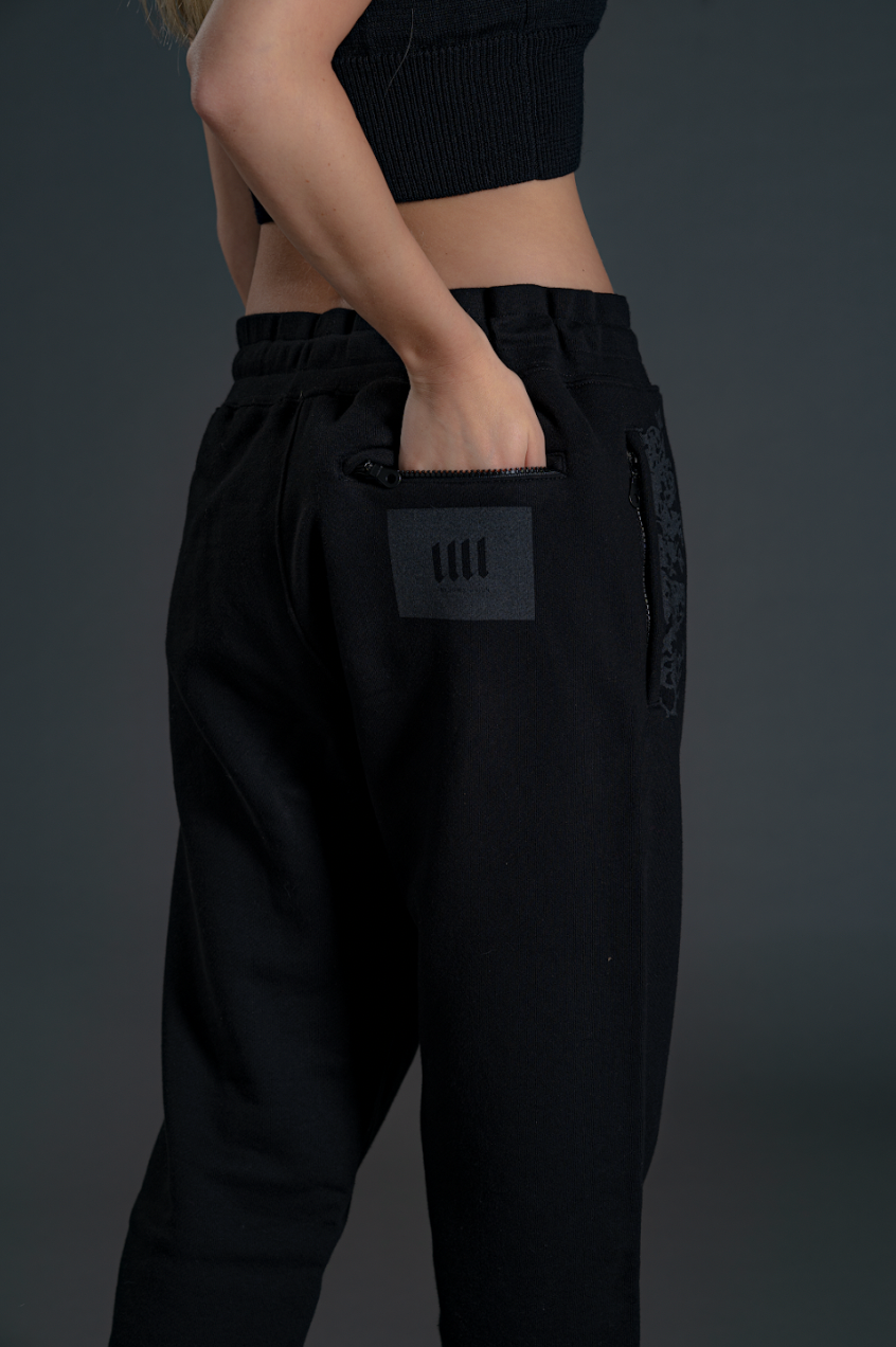 Person wearing black pants with a pocket patch on a dark background