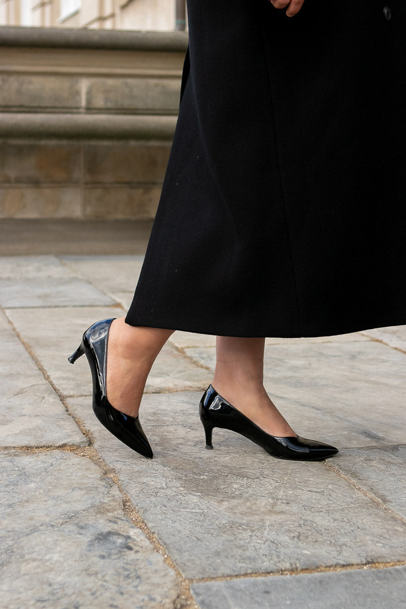 Person wearing black high-heeled shoes on a stone pavement.