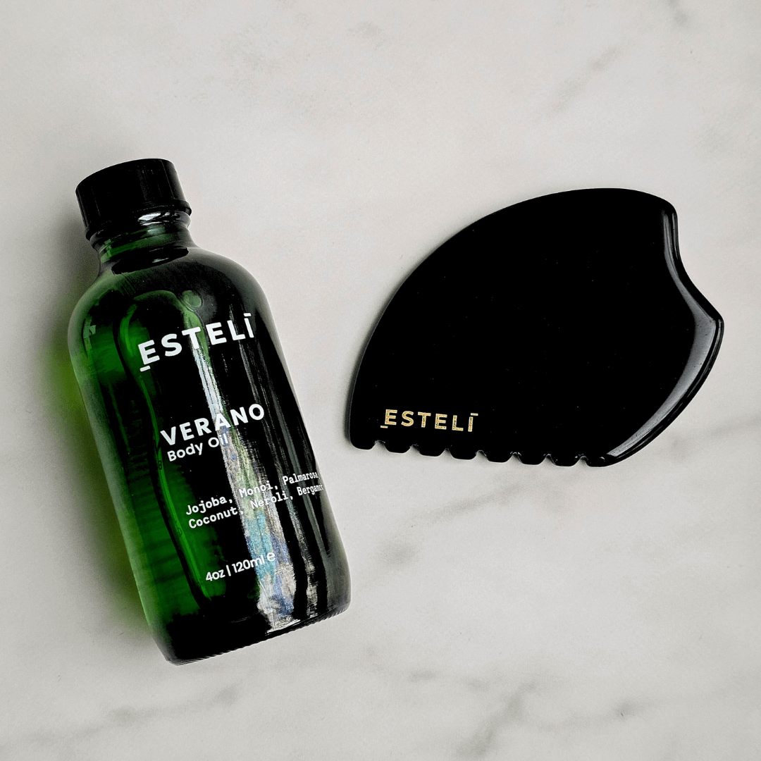 Estelé body oil bottle and black grooming tool on a light background