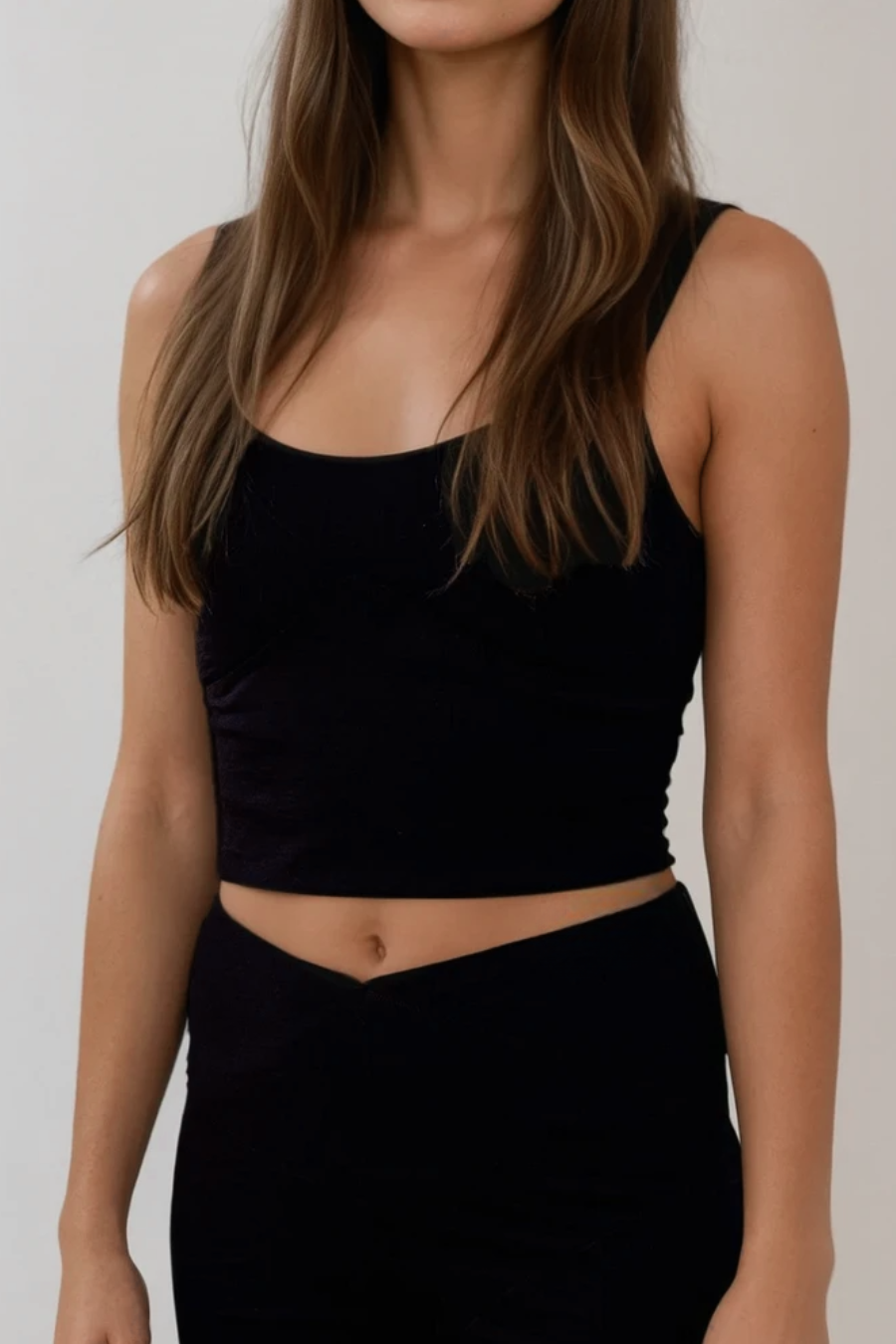 Person wearing a black sleeveless top and skirt against a plain background