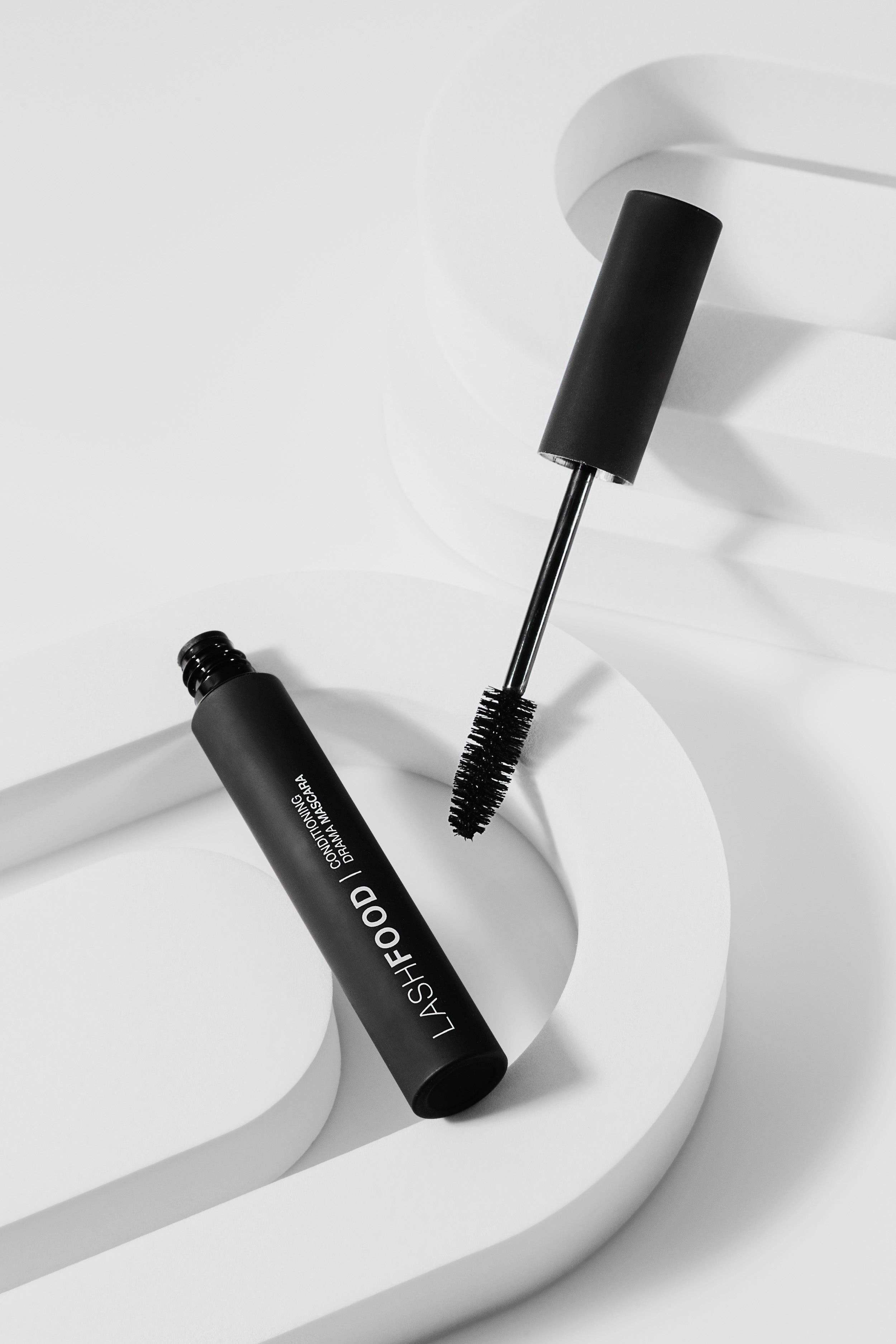 Black mascara tube with brush on a white background
