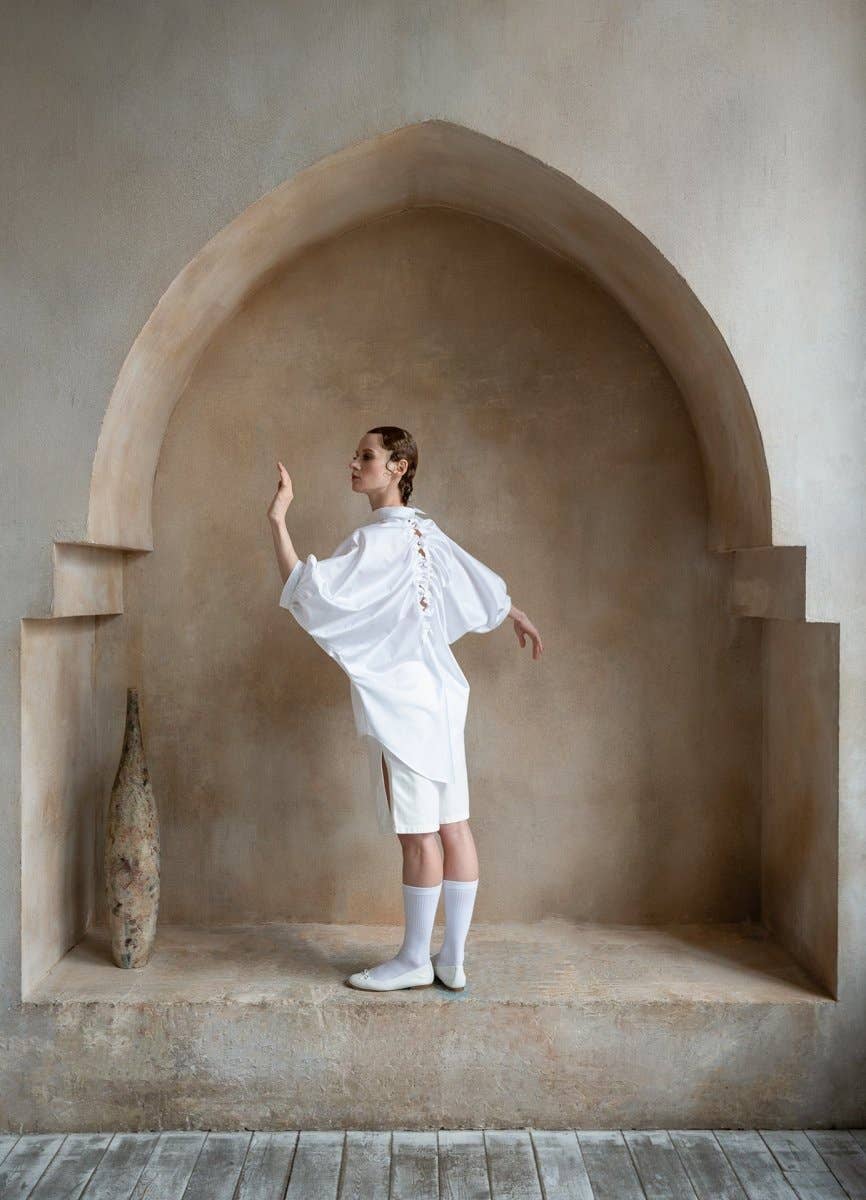 Person in a white outfit standing in a stone archway