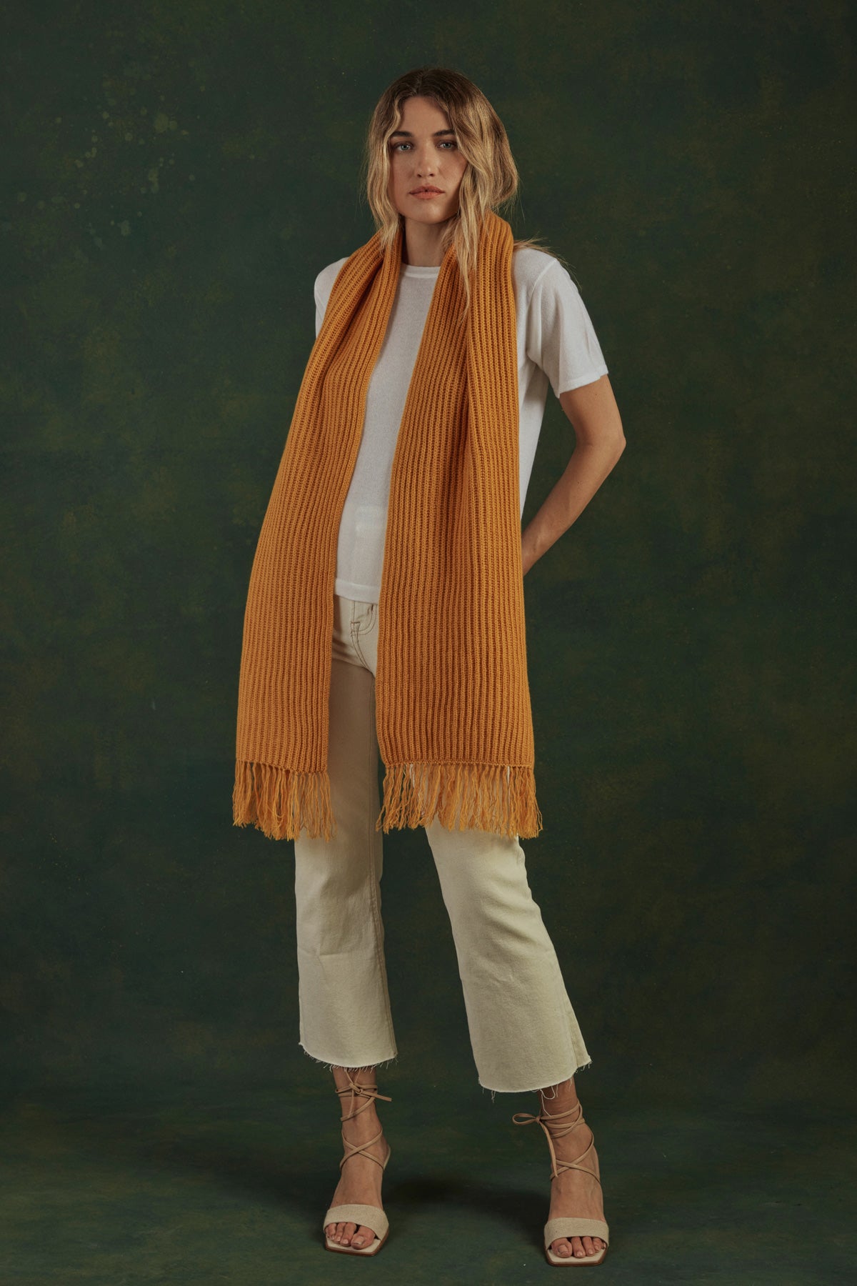 Woman wearing a mustard yellow scarf against a dark green background