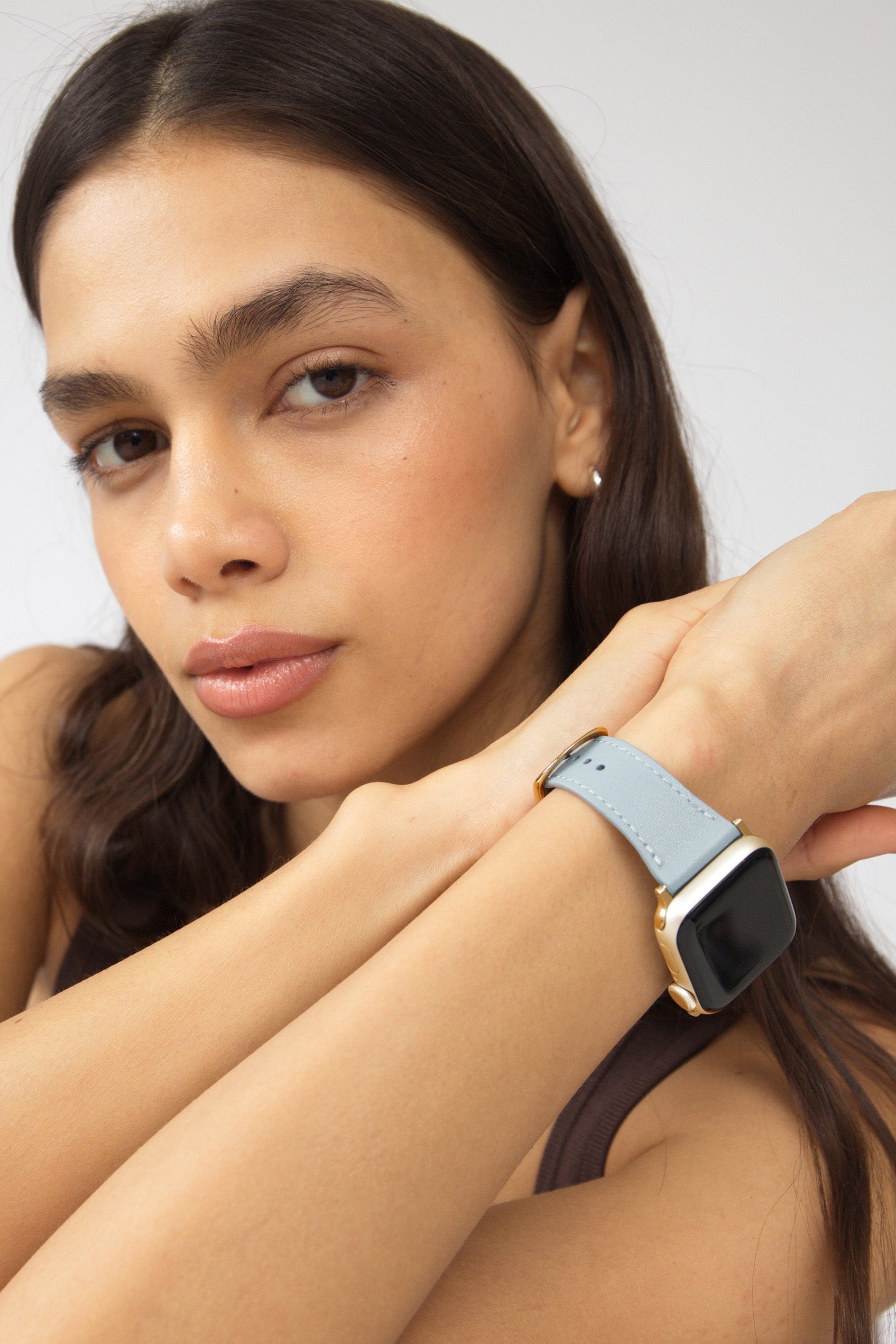 Woman wearing a smartwatch on her wrist with a neutral background