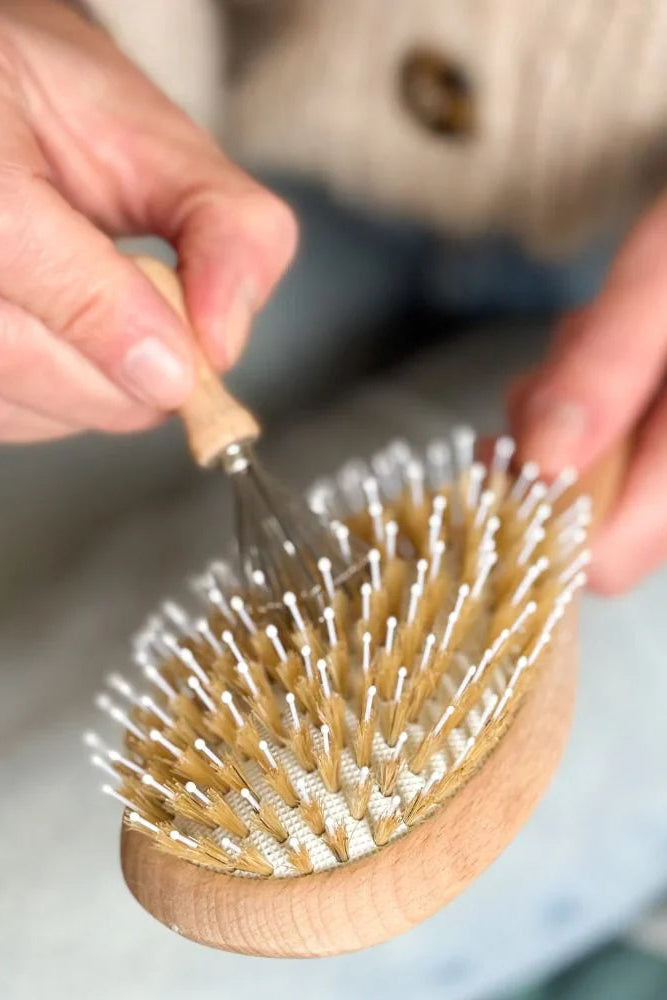 Person using a wooden hairbrush with bristles on a blurred background