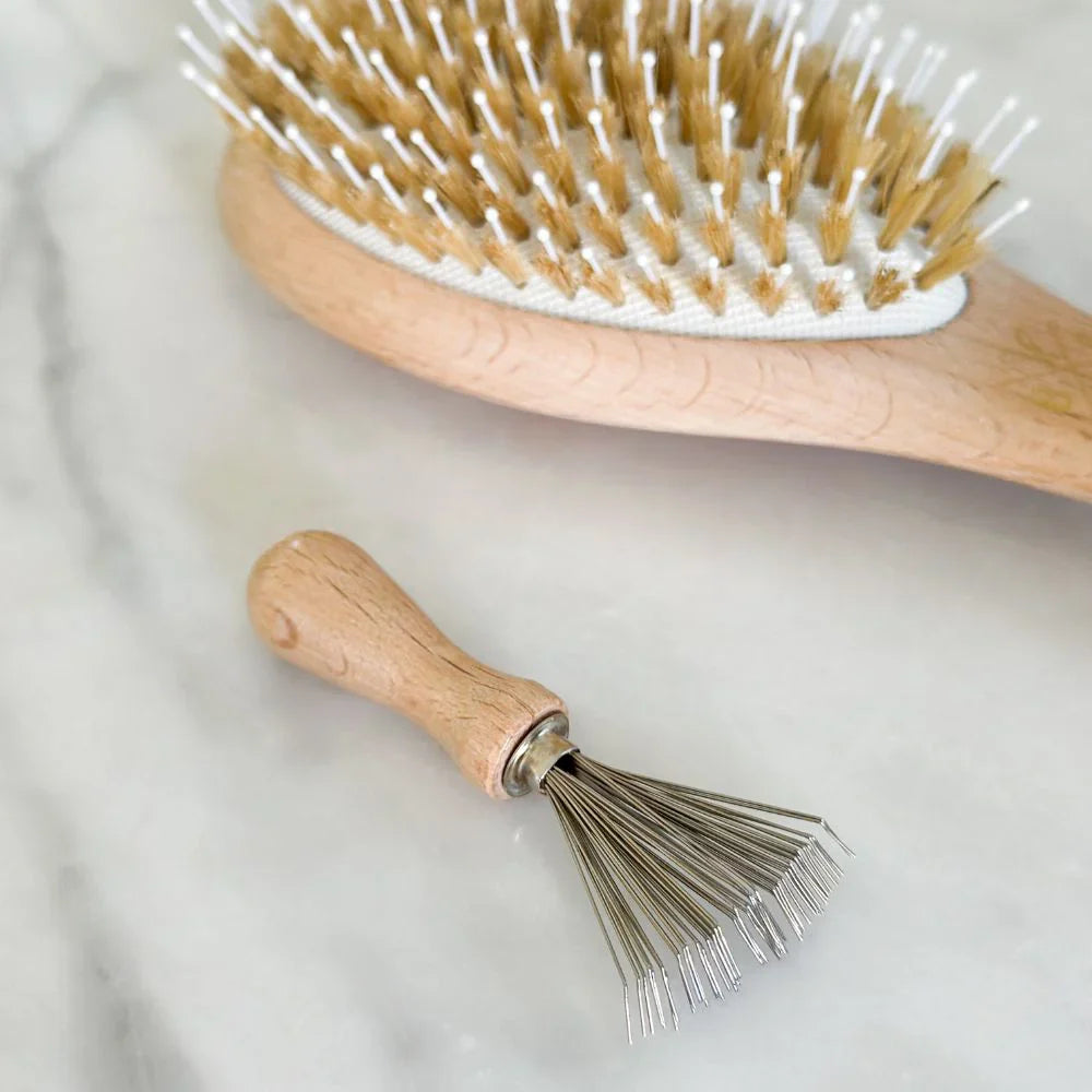 Wooden hairbrush with bristles and metal brush on a light background