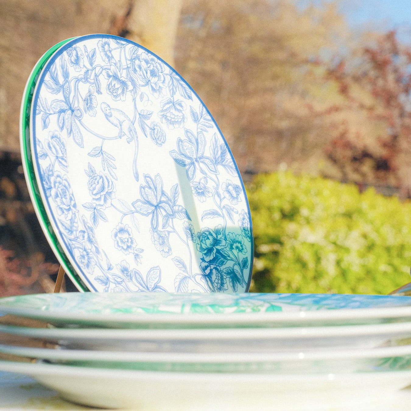 Stack of floral-patterned plates with a blurred outdoor background