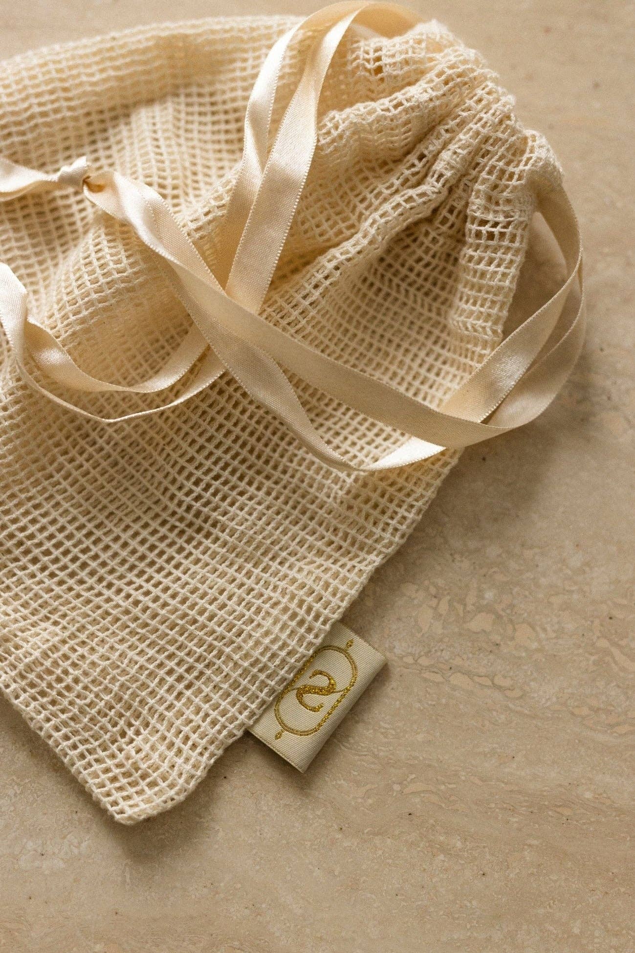 Beige mesh bag with ribbon on a beige background