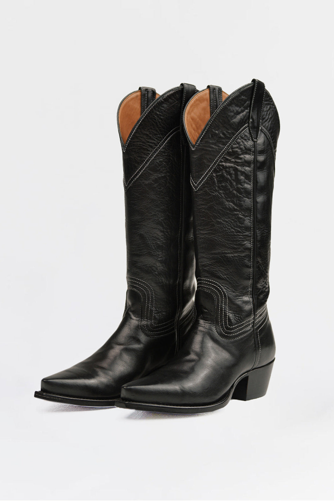 A pair of black leather cowboy boots with pointed toes and low block heels, shown from a three-quarter angle against a light gray background.