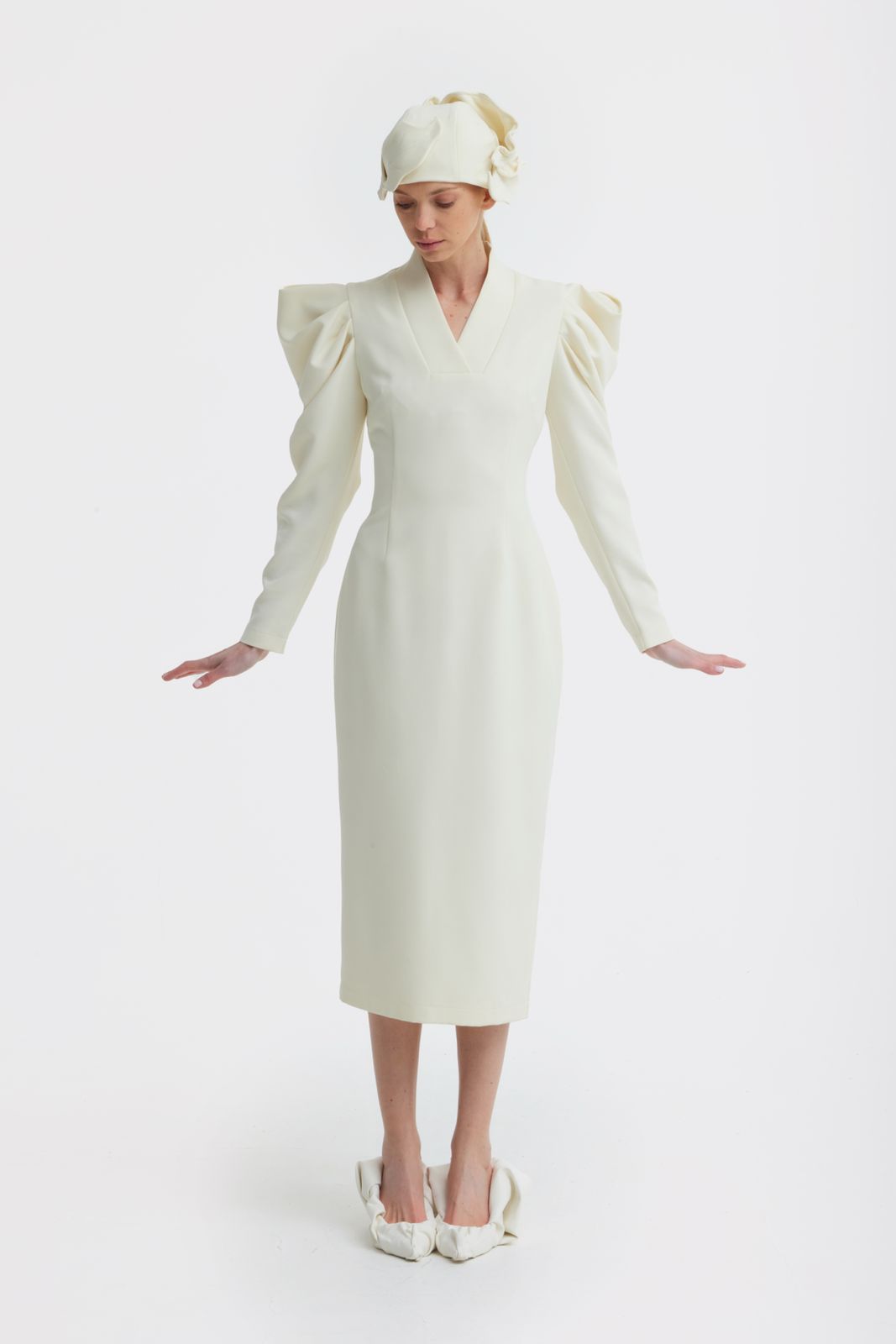 Person wearing a white dress with puffed sleeves and a matching headscarf on a white background