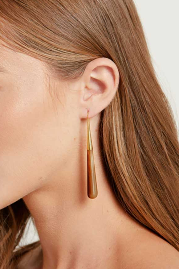 Woman wearing gold earrings with a plain background