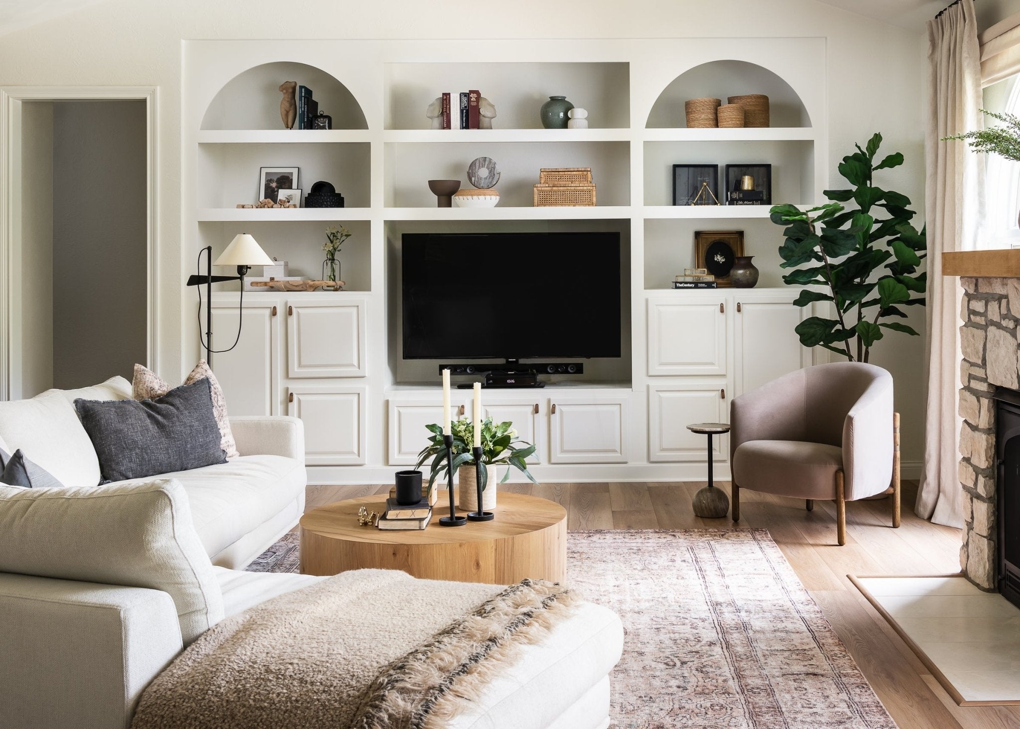 Modern living room with white walls, a white sofa, and a television mounted on a wall unit.