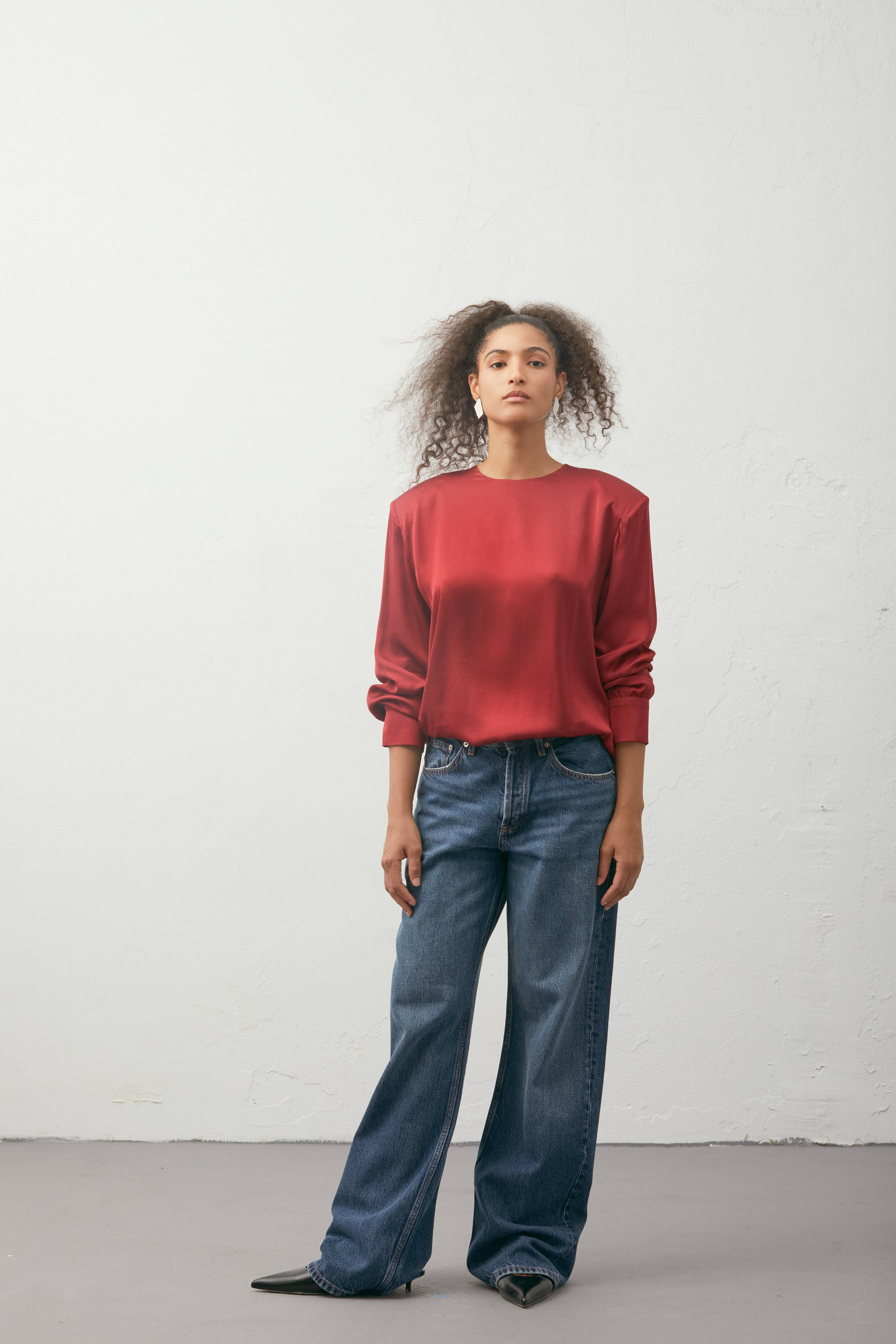 Person wearing a red shirt and blue jeans against a white background