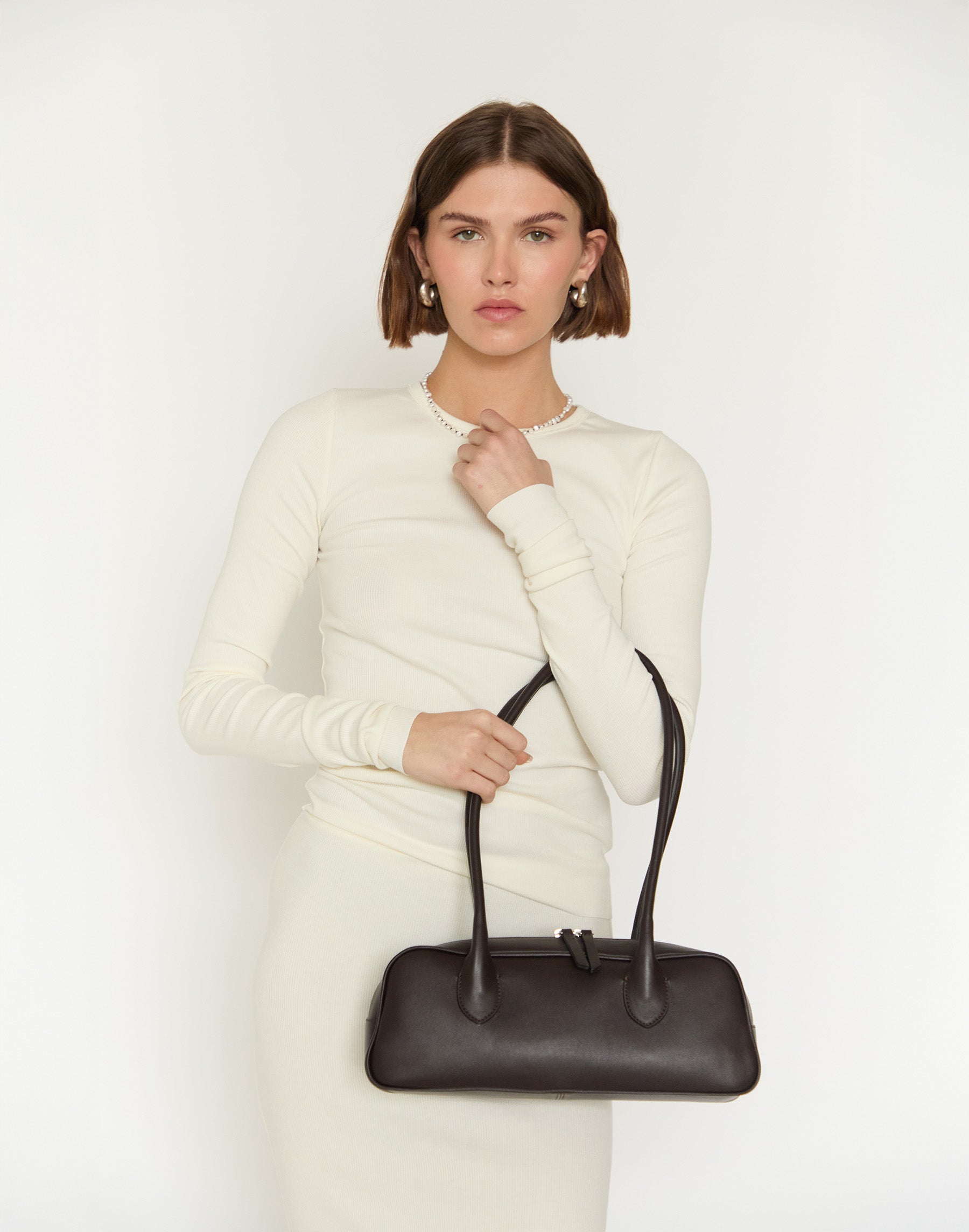 Woman holding a black handbag against a white background