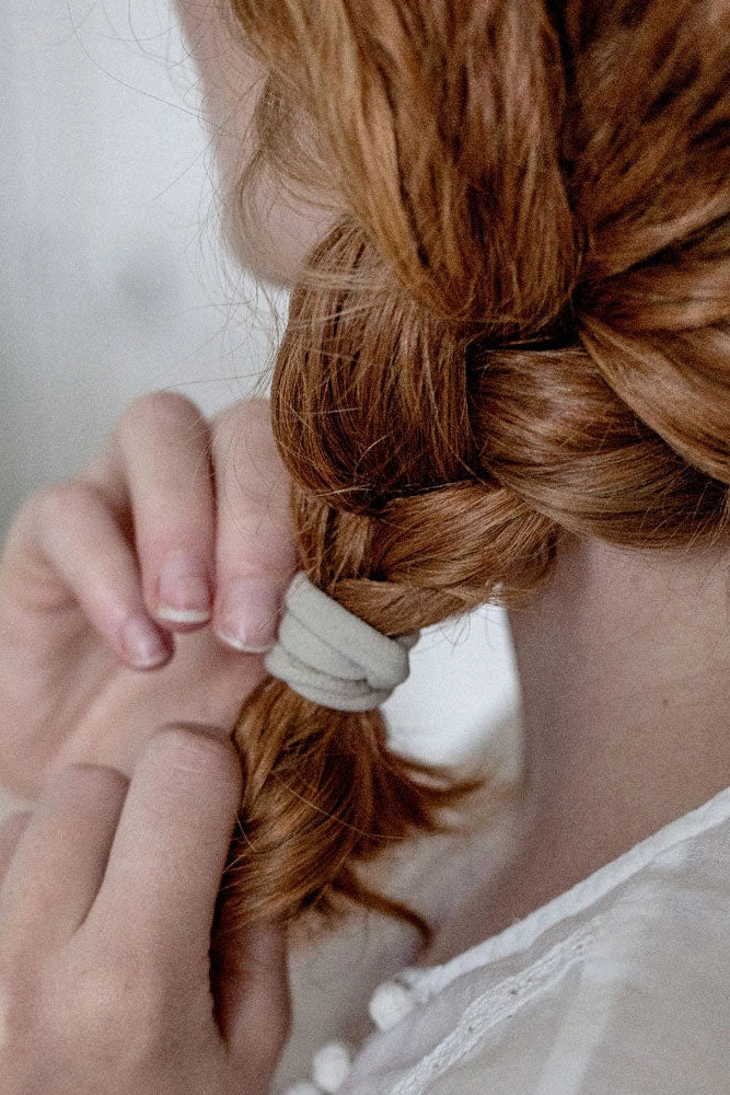 Person braiding red hair with a blurred background
