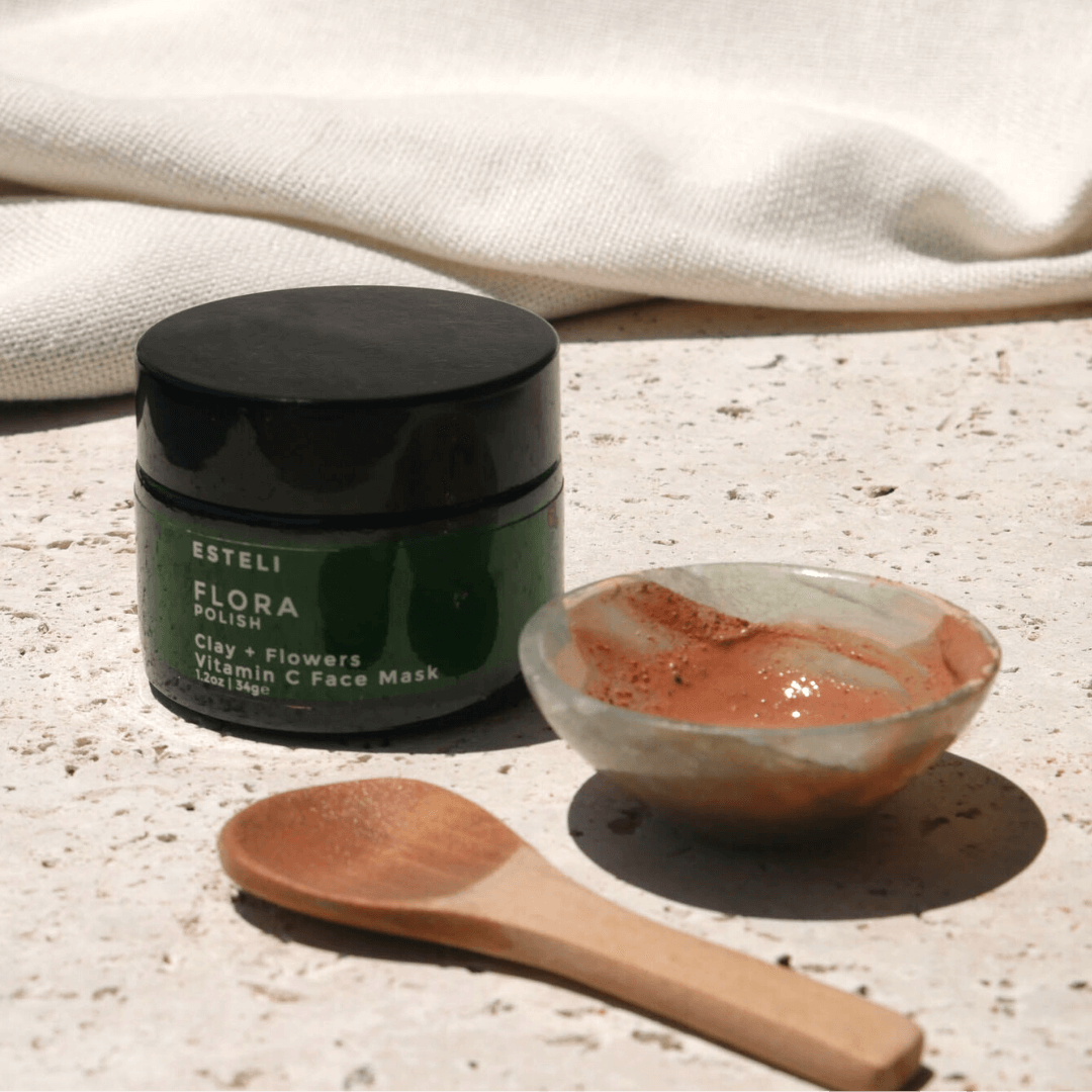 Esteli Flora Polish face mask jar with a wooden spoon and small bowl on a textured surface.