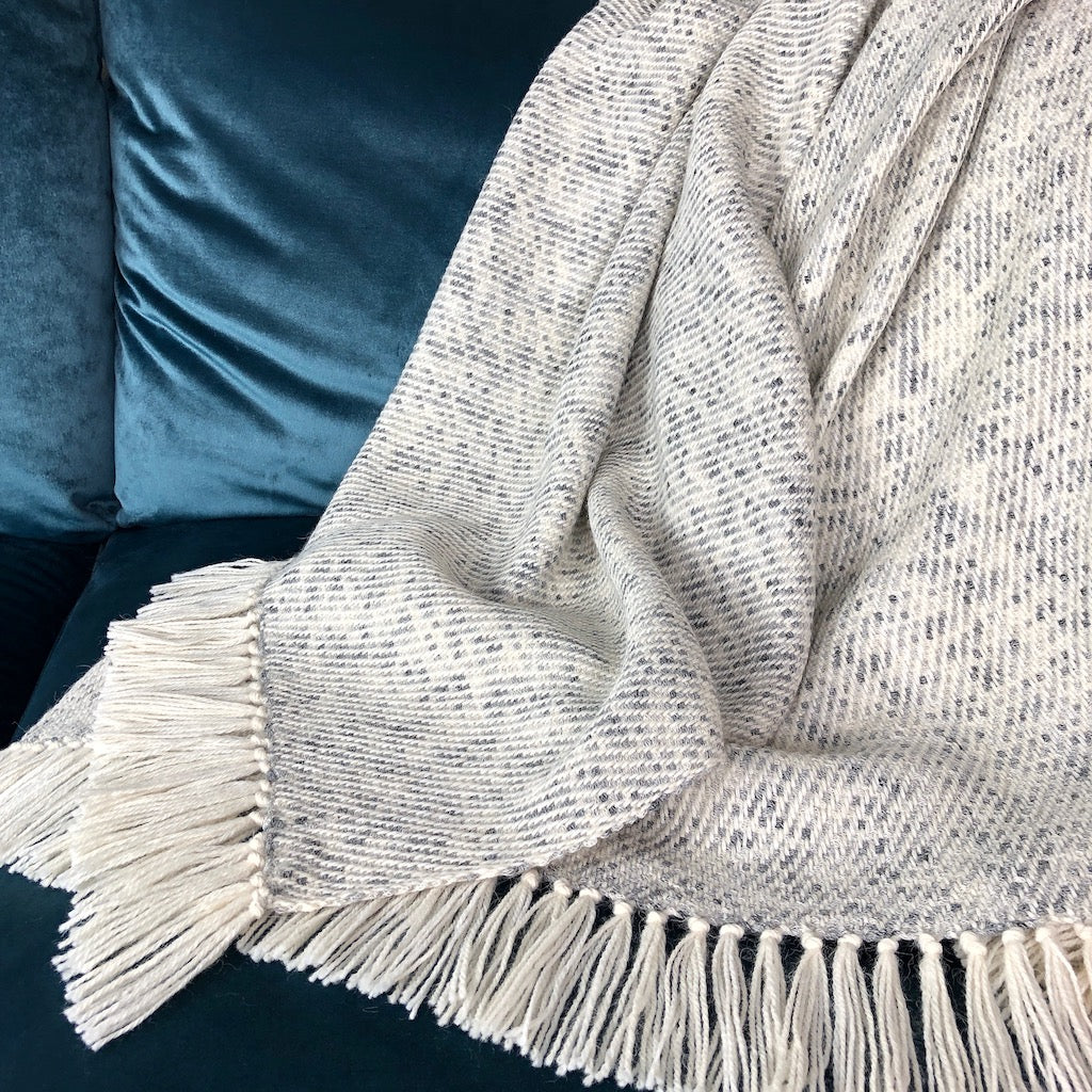 Textured blanket with fringe draped over a blue cushioned surface