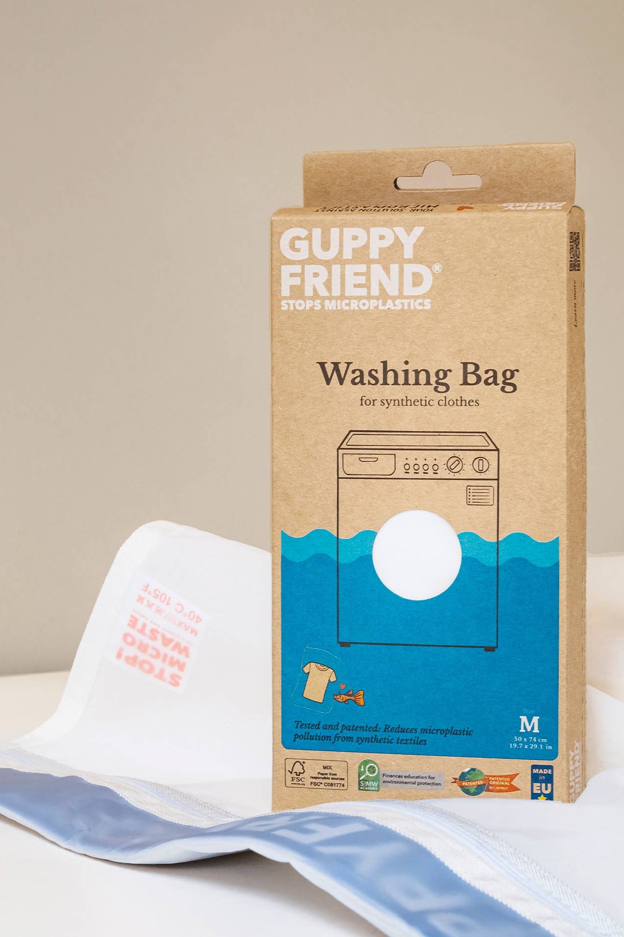 Guppy Friend washing bag packaging with a white bag on a beige background
