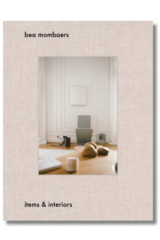 Book cover with 'bea mombaers' and 'items & interiors' text, featuring a minimalistic interior design scene.