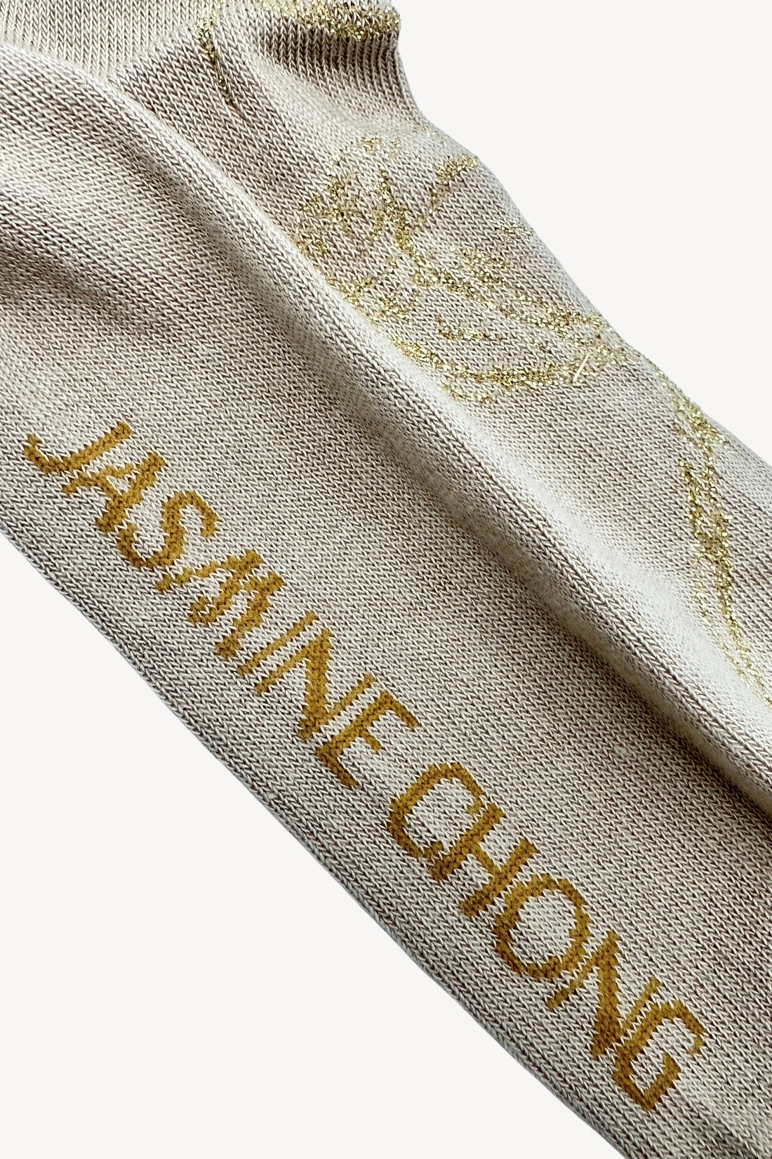 Beige sock with gold text on a white background