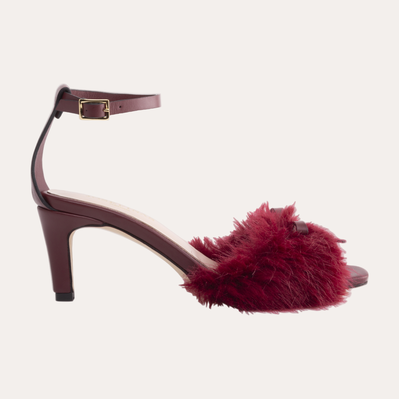 Burgundy high-heeled shoe with fur detail on a white background