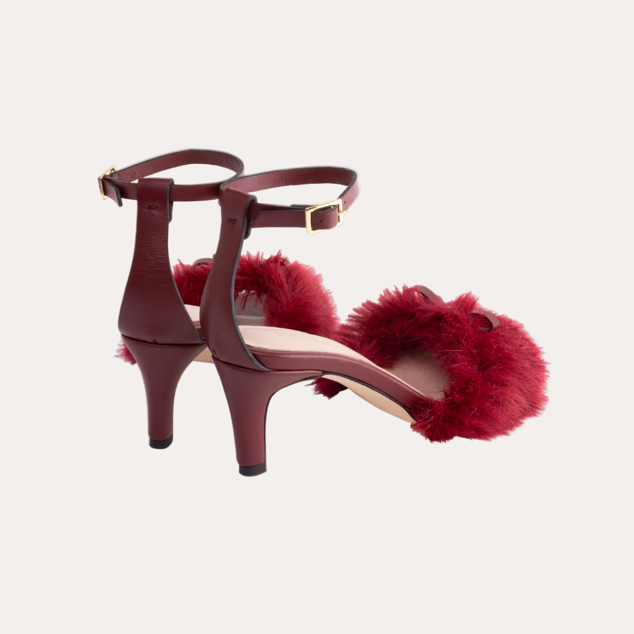 Red high-heeled shoes with fur pom-poms on a white background