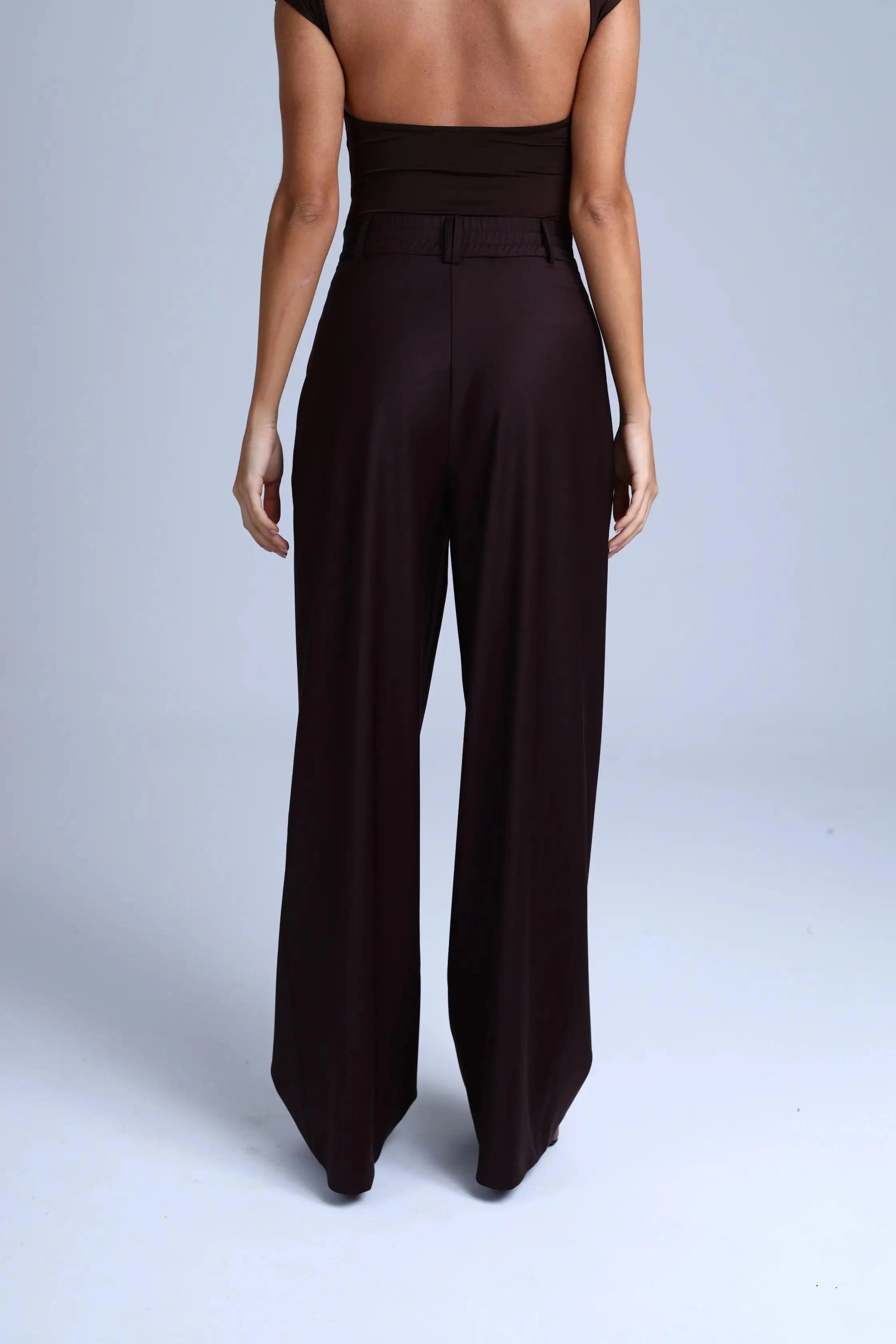 Person wearing brown high-waisted pants on a light gray background