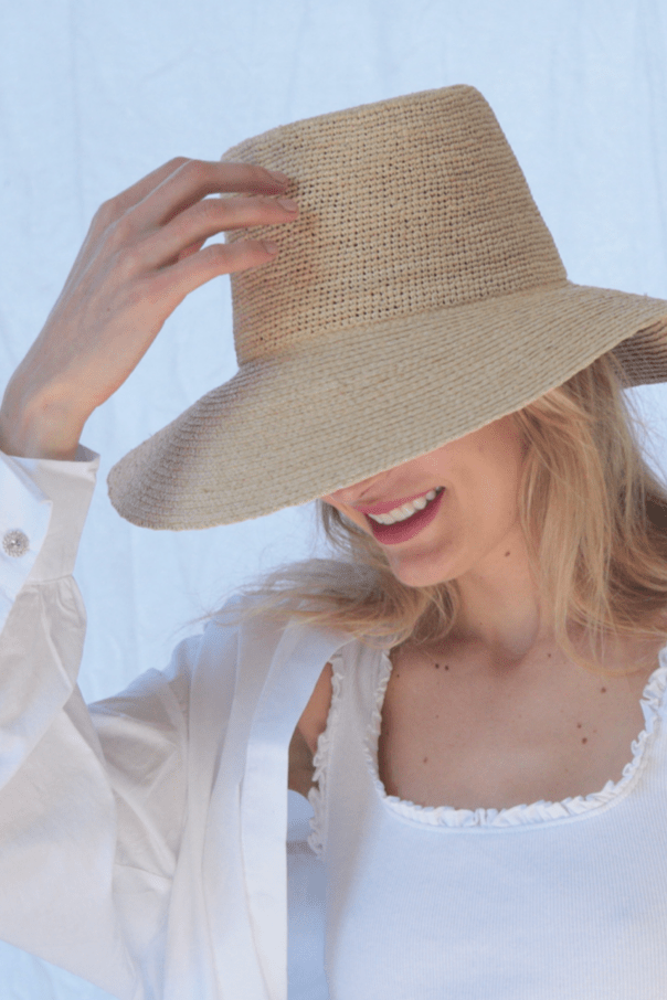 Woman wearing a straw hat against a light blue background