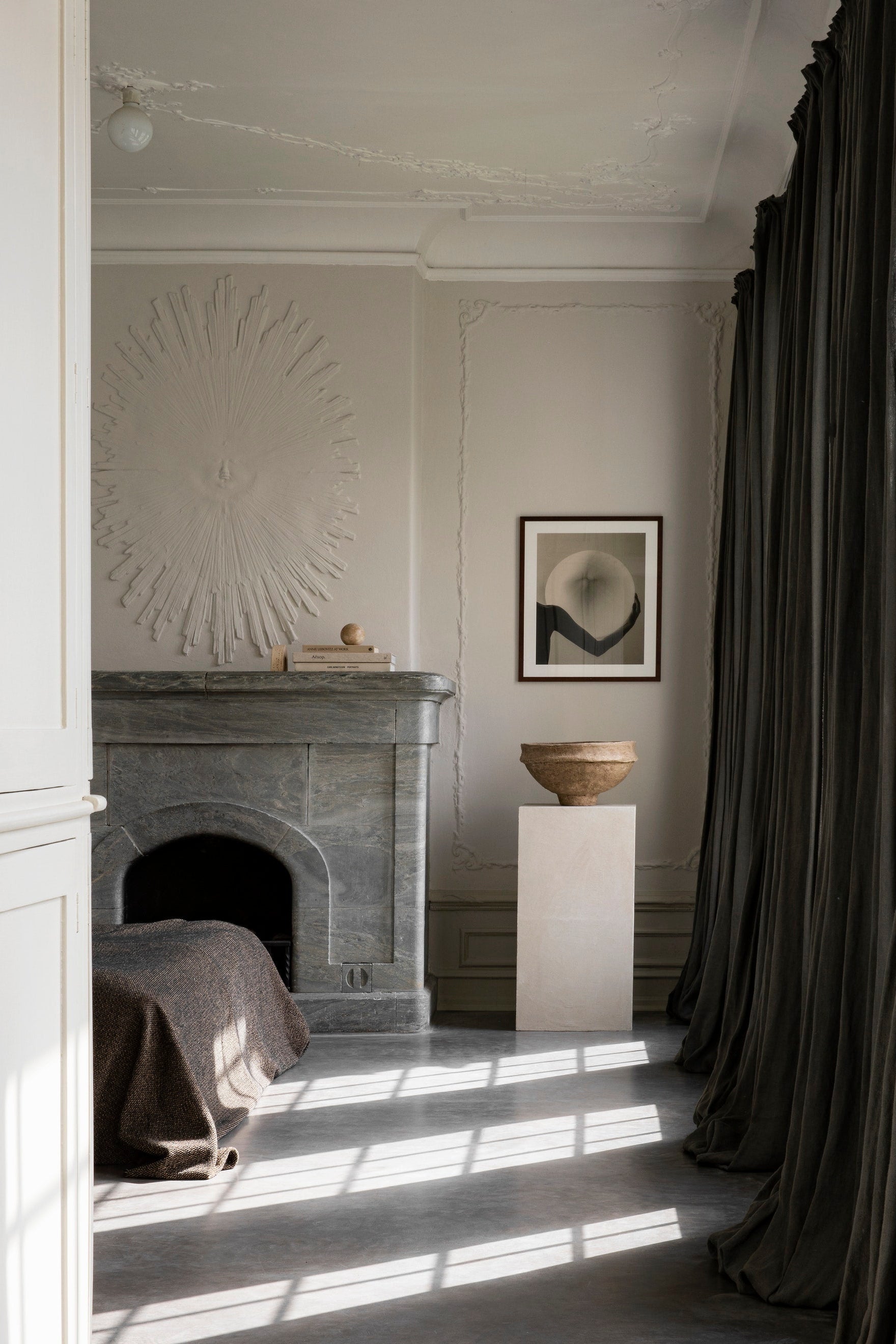 Neatly arranged room with a fireplace, artwork, and large curtain.