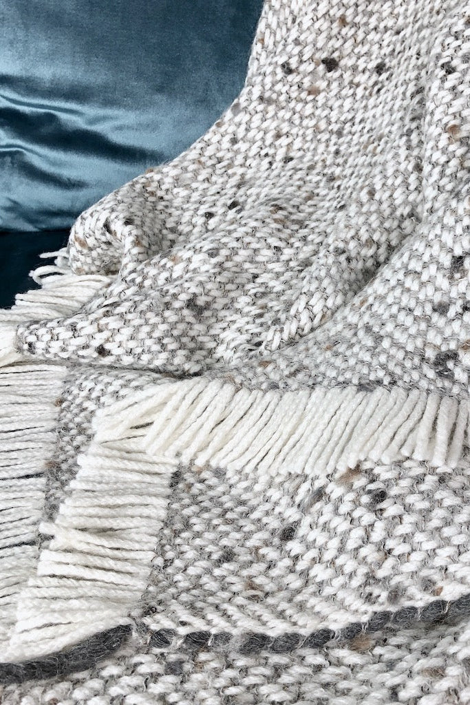 Textured blanket with fringe on a blue fabric background