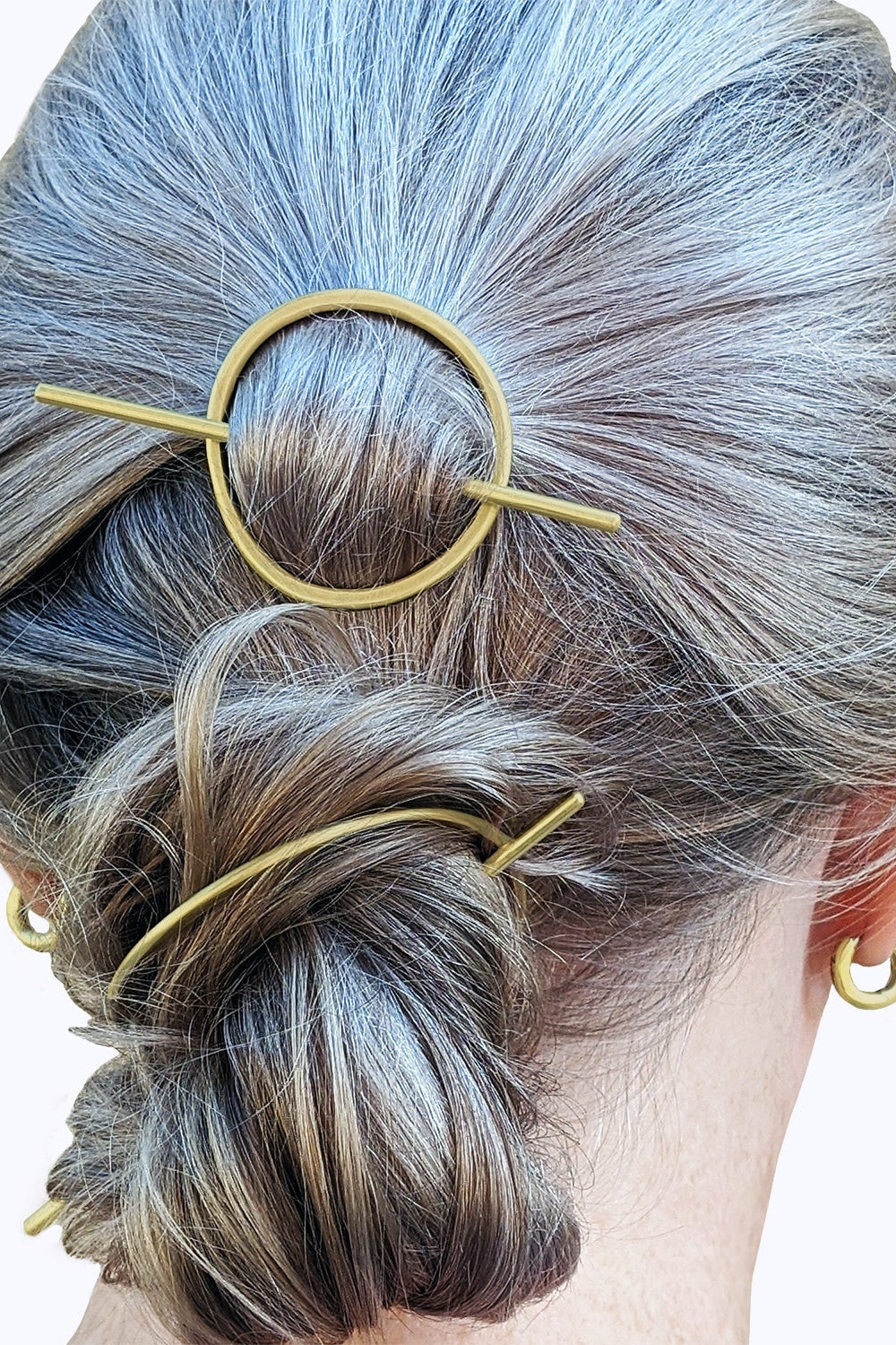 Person with styled hair using gold hairpins on a white background