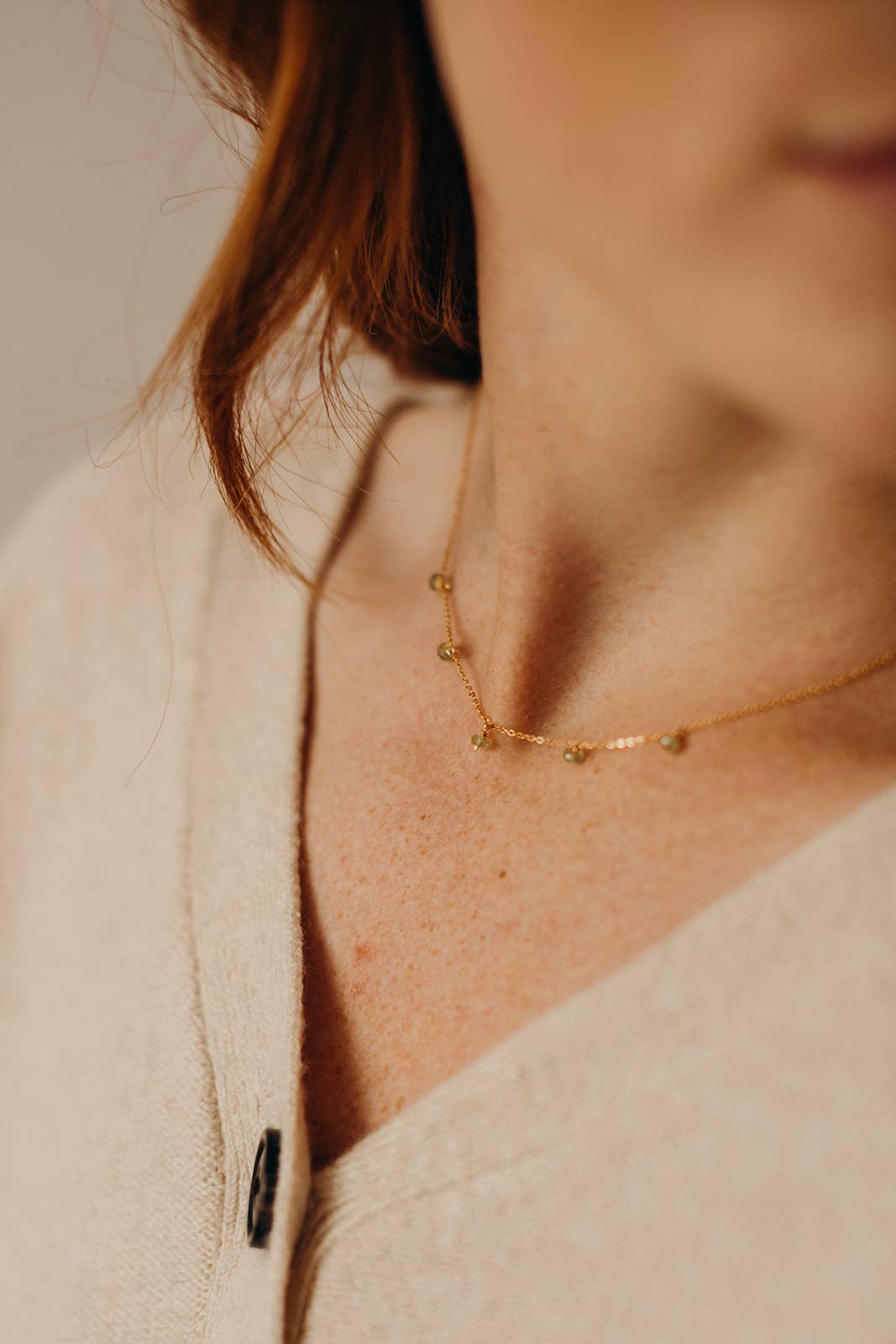 Woman wearing a small labradorite necklace.
