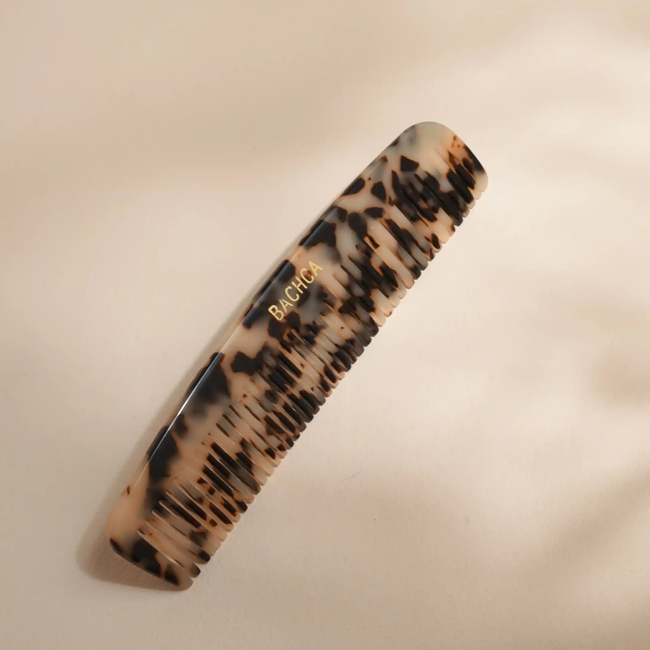 Tortoiseshell comb with 'Bachca' branding on a beige background
