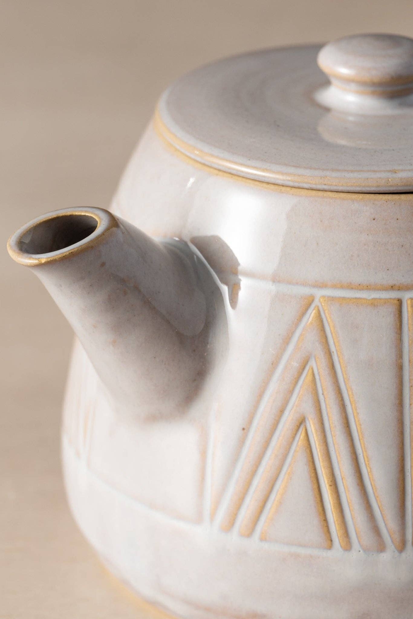 Ceramic teapot with geometric patterns on a beige background