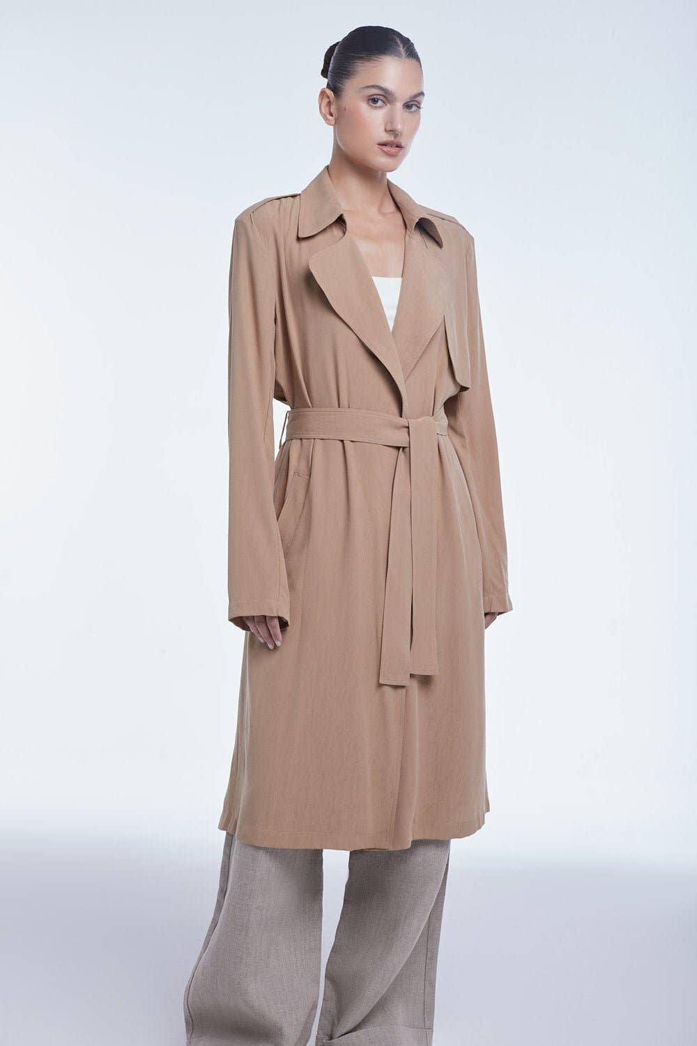 Woman wearing a beige trench coat on a white background