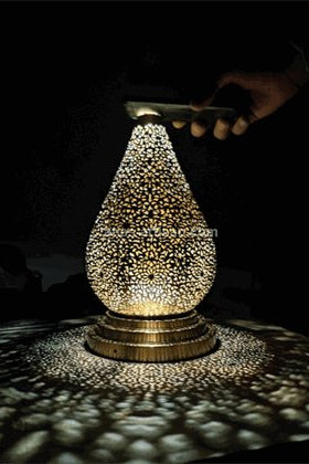 Decorative lamp with intricate design casting shadows on a dark surface