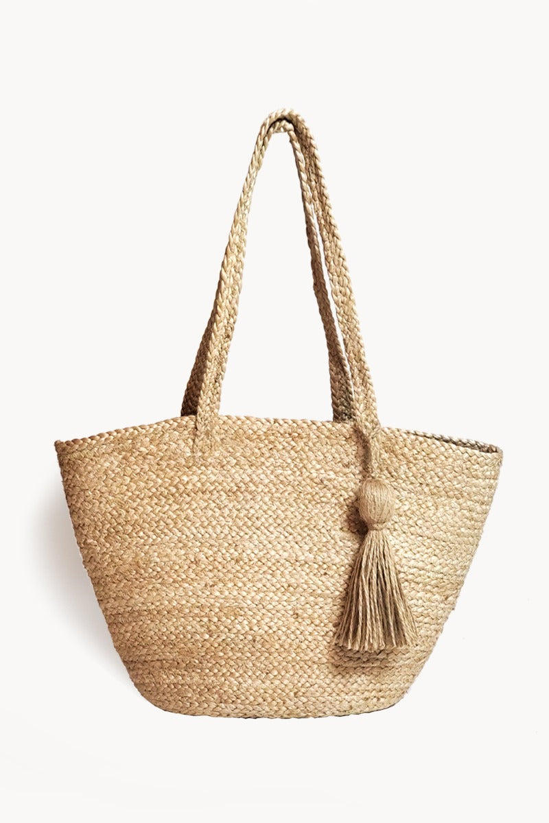 Woven straw tote bag with a tassel on a white background