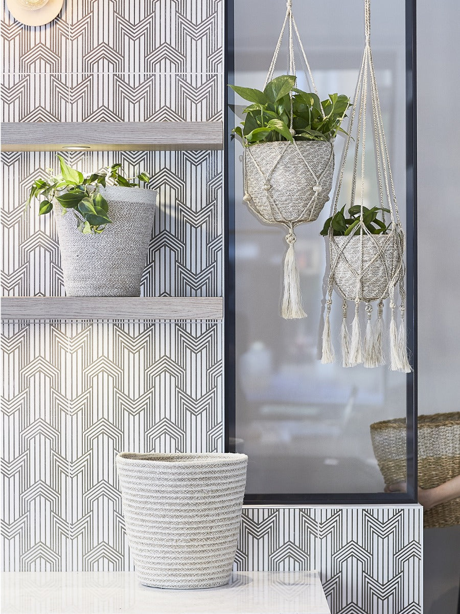 Decorative wall with geometric pattern, hanging planters, and textured plant pots.