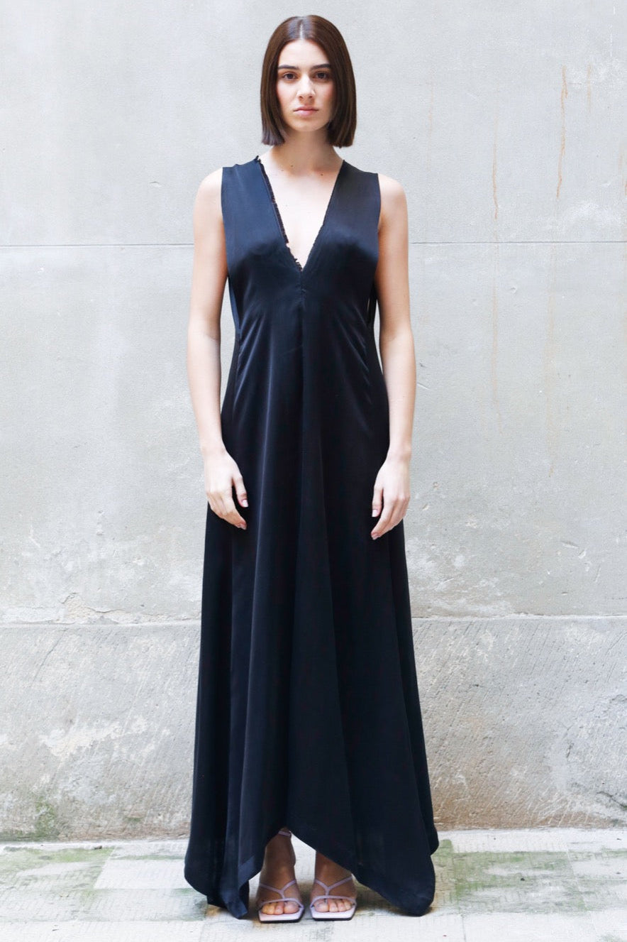 Woman wearing a black sleeveless dress against a gray wall.