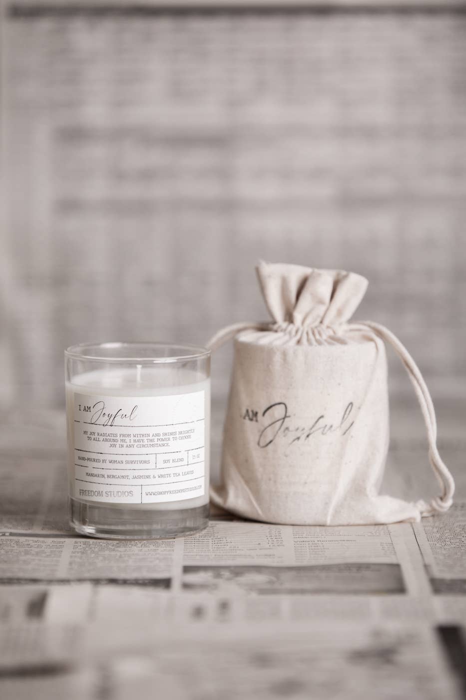 Candle and drawstring bag labeled 'I am Grateful' on a textured surface.